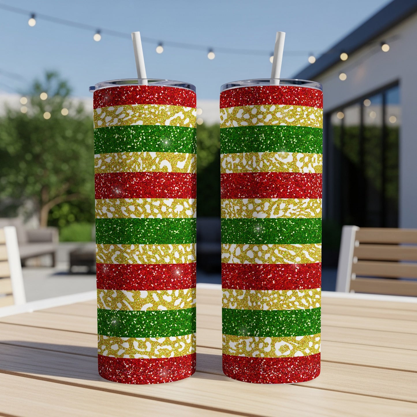 Two glittery tumblers with red, gold, and green stripes sit on a table.