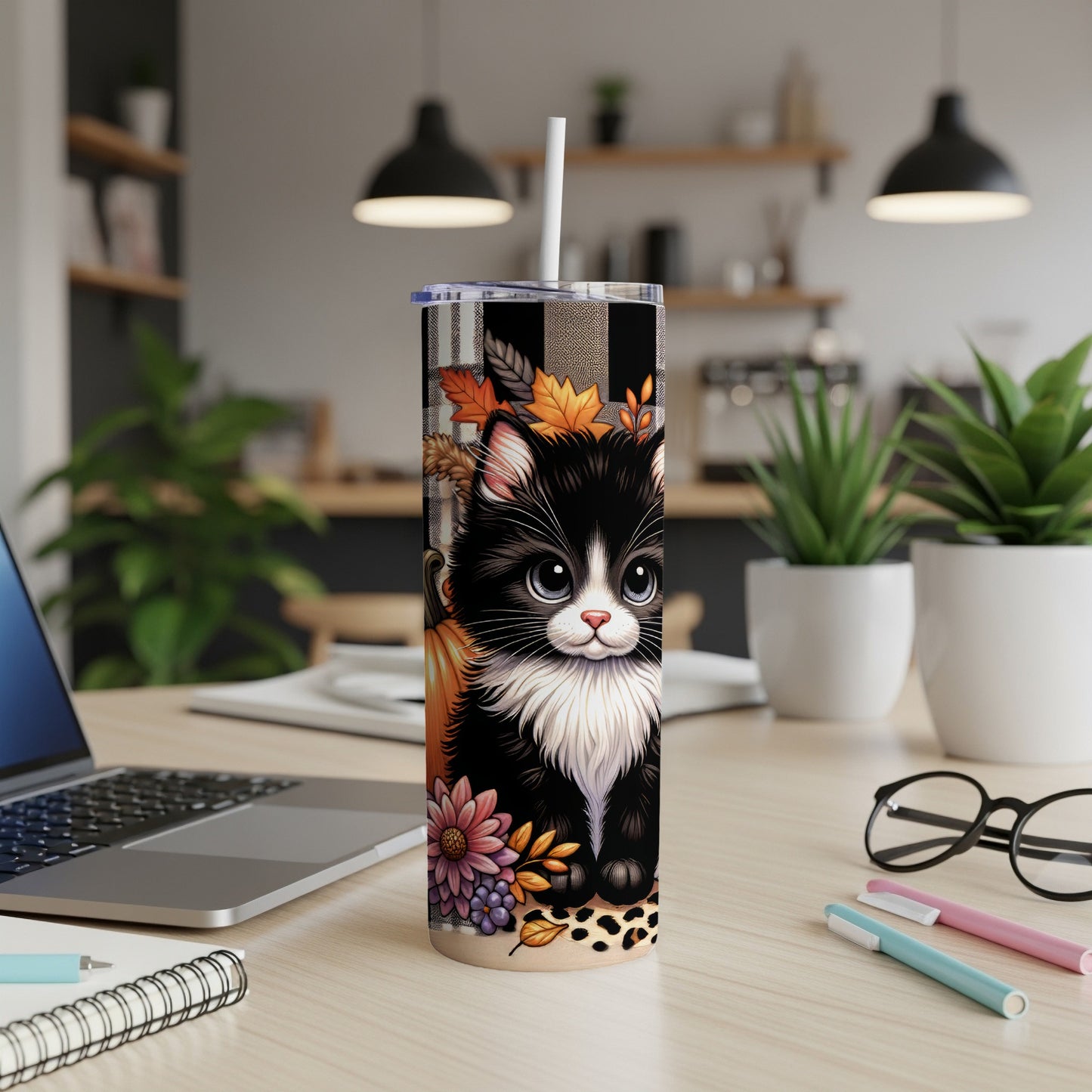 Black and white cat wearing plaid scarf and autumn leaves on tumbler.