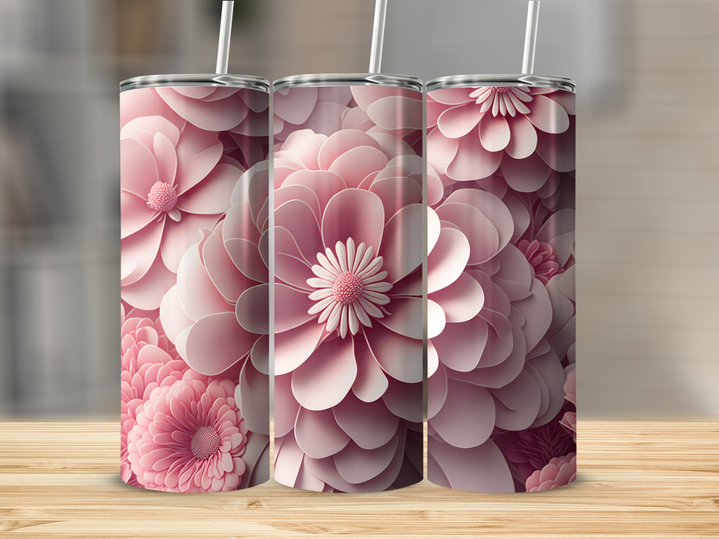 Three pink floral tumblers with straws on a wooden surface.