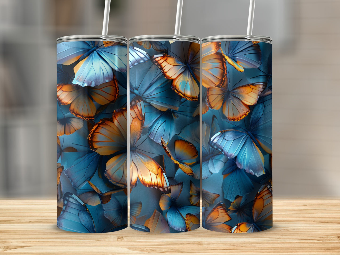 Three blue and orange butterfly pattern tumblers on a wooden surface.