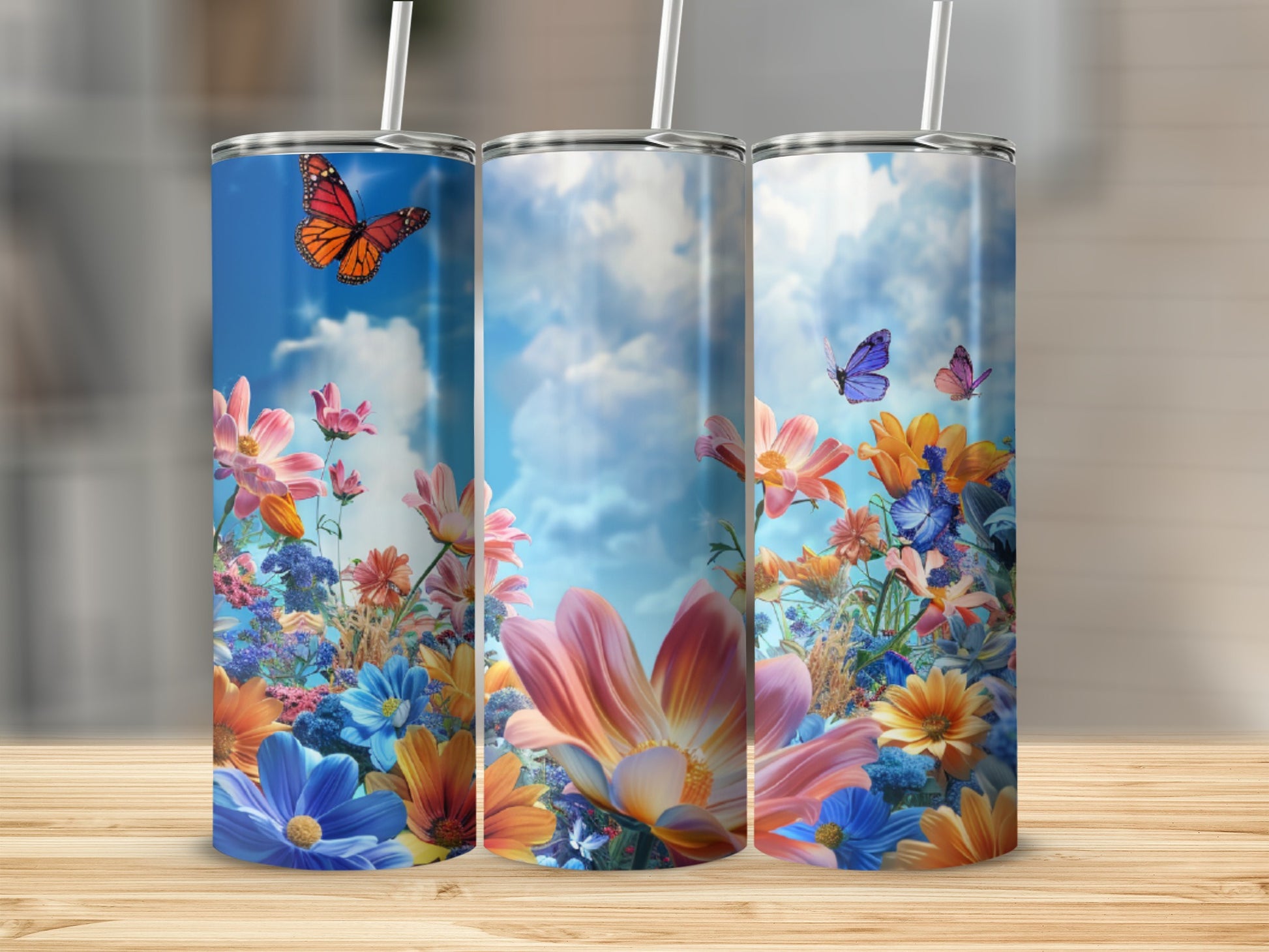 Three tumblers featuring colorful wildflowers and butterflies against a blue sky.