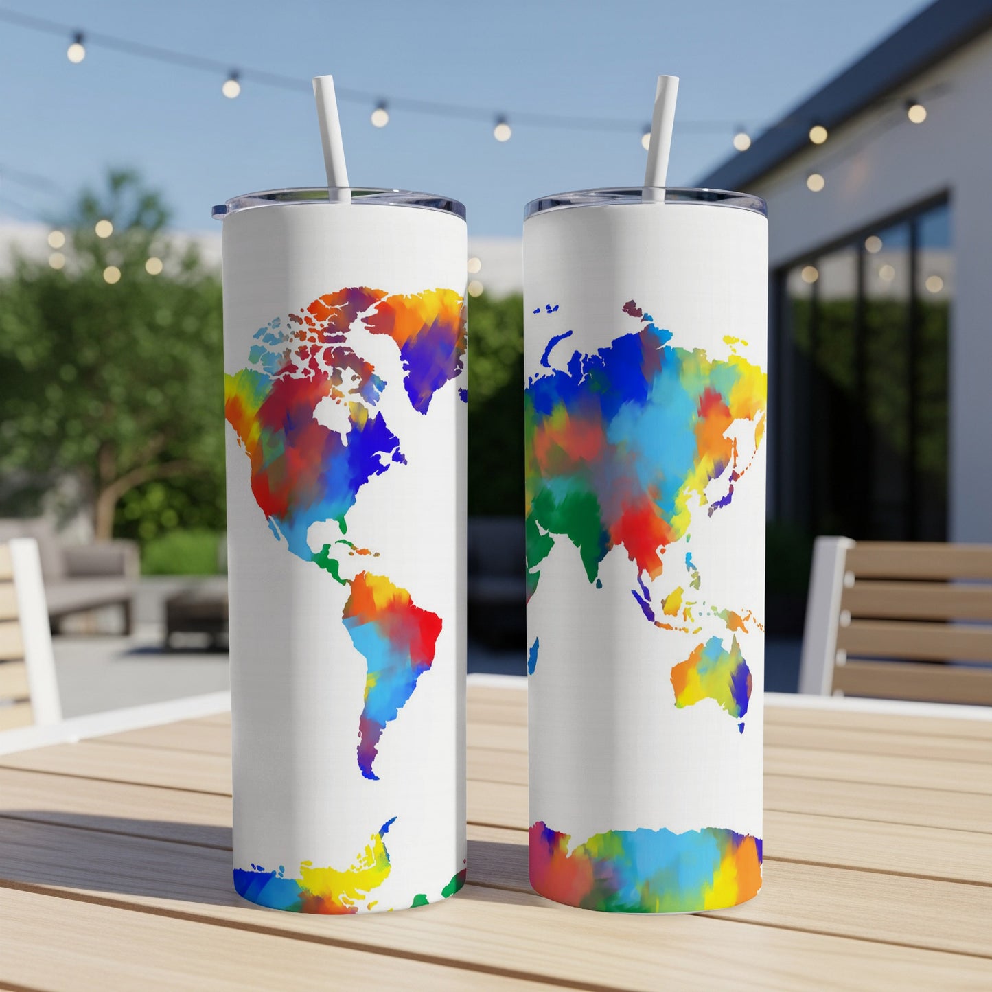 Two white tumblers with colorful world map design and straws on a table.