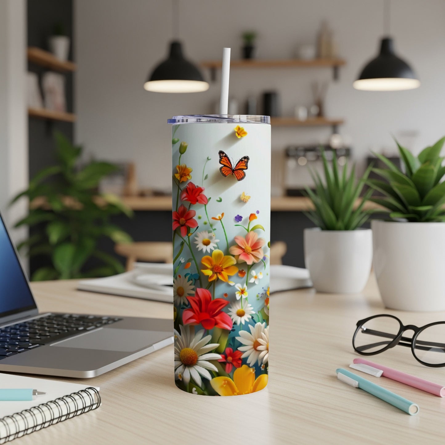 Floral pattern tumbler with butterfly, on a desk next to a laptop.