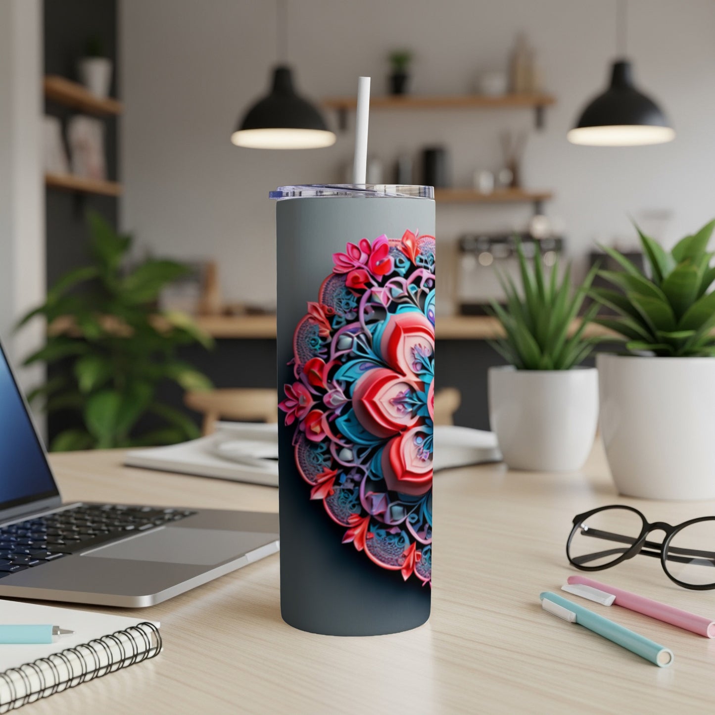 Gray tumbler with colorful floral mandala design on a desk.