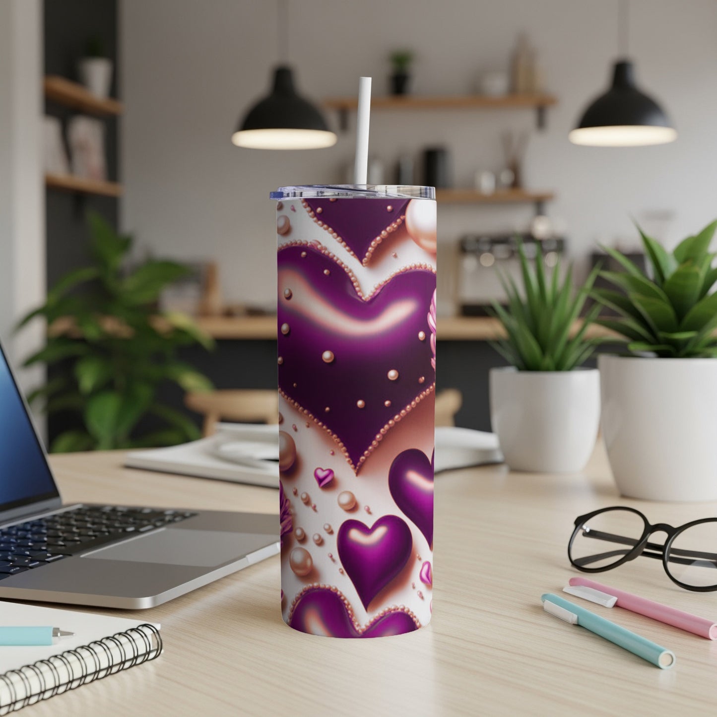 Purple and pink heart-patterned tumbler with straw on desk.