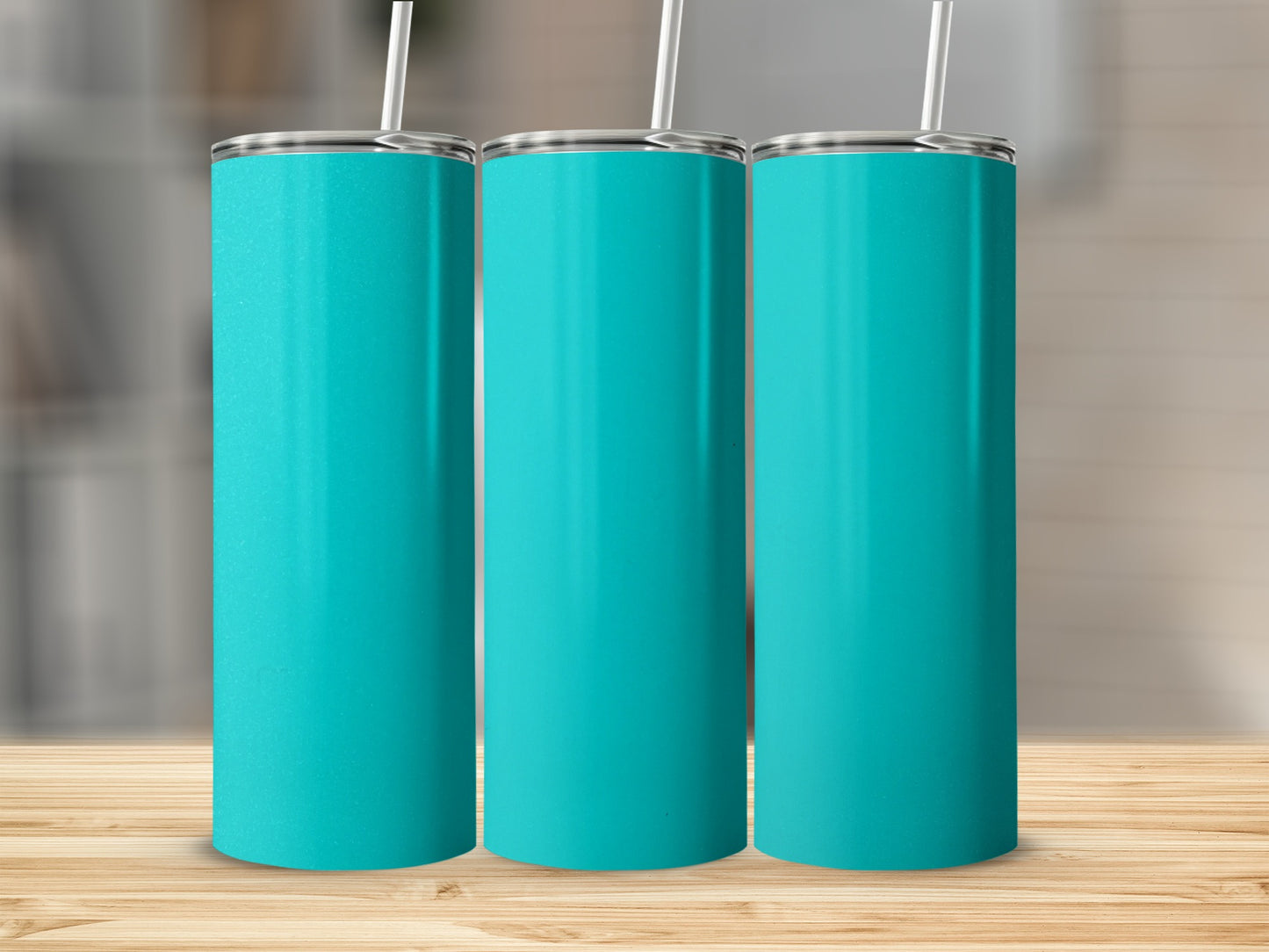 Three teal tumblers with straws stand on a wooden surface.