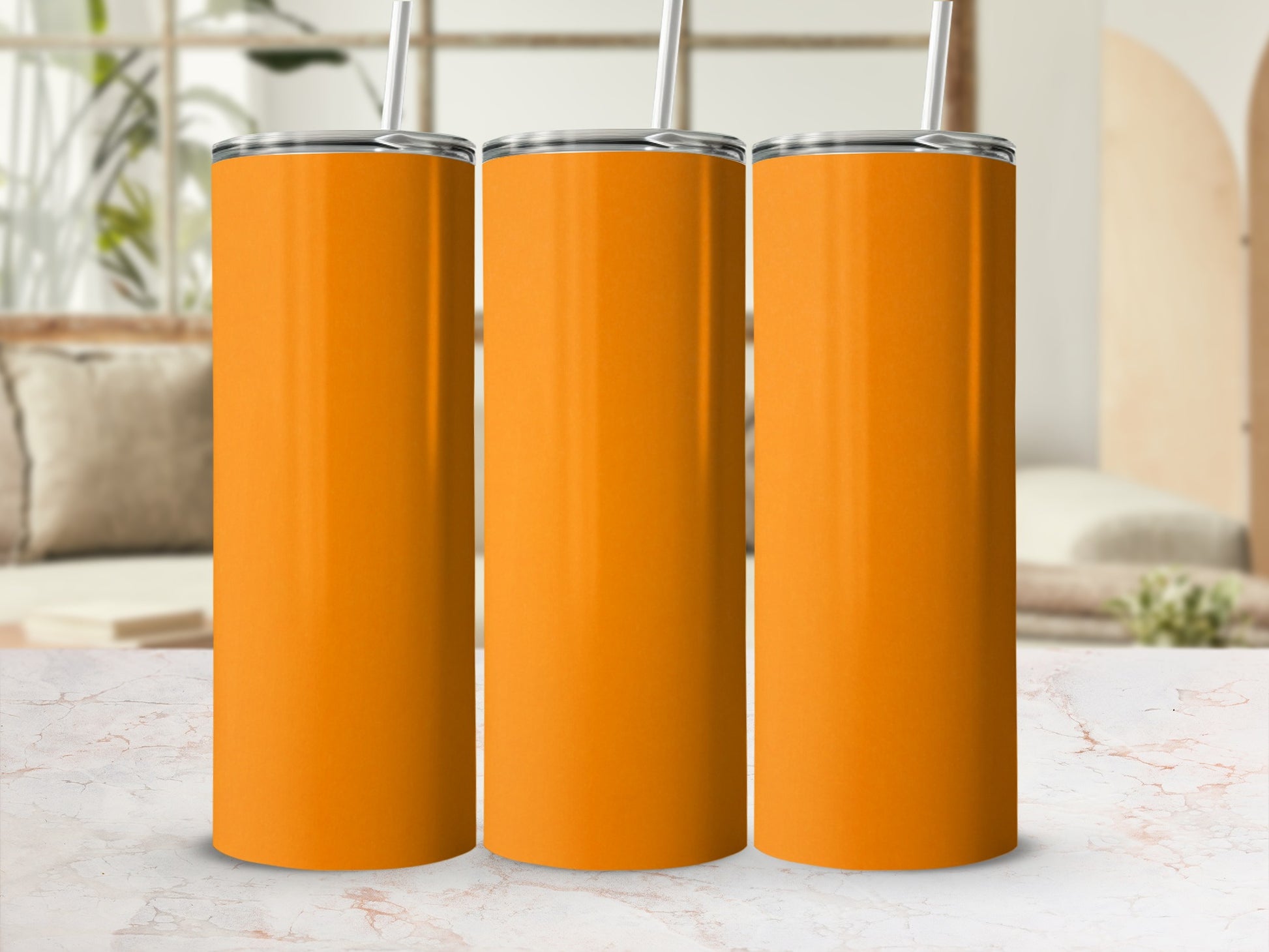 Three plain orange tumblers with straws stand side-by-side.