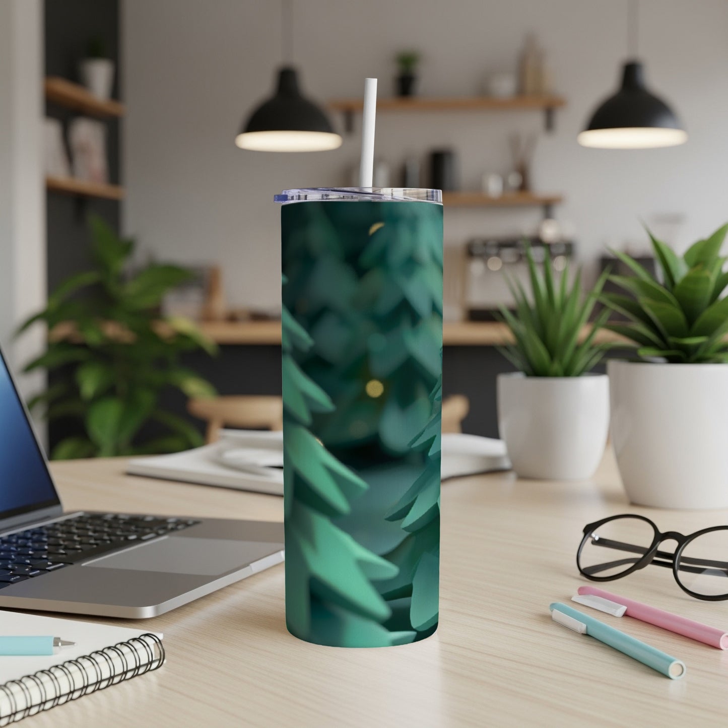 Green pine needles cover a stainless steel tumbler on a desk.