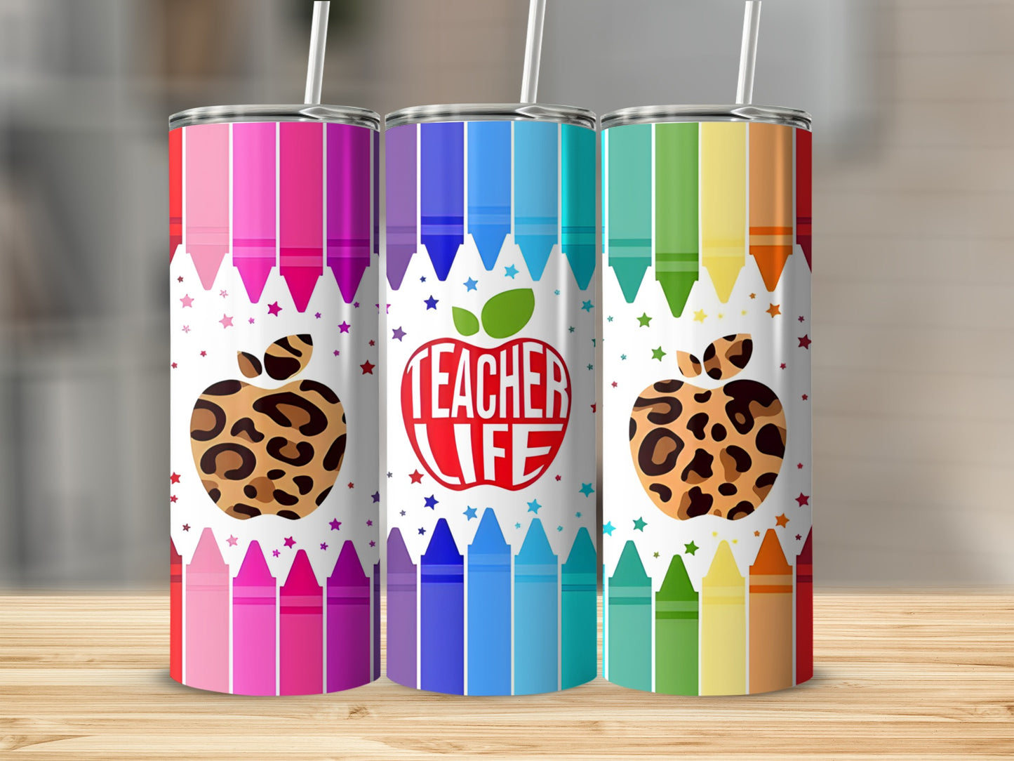Three tumblers with crayon and apple designs on a wooden surface.