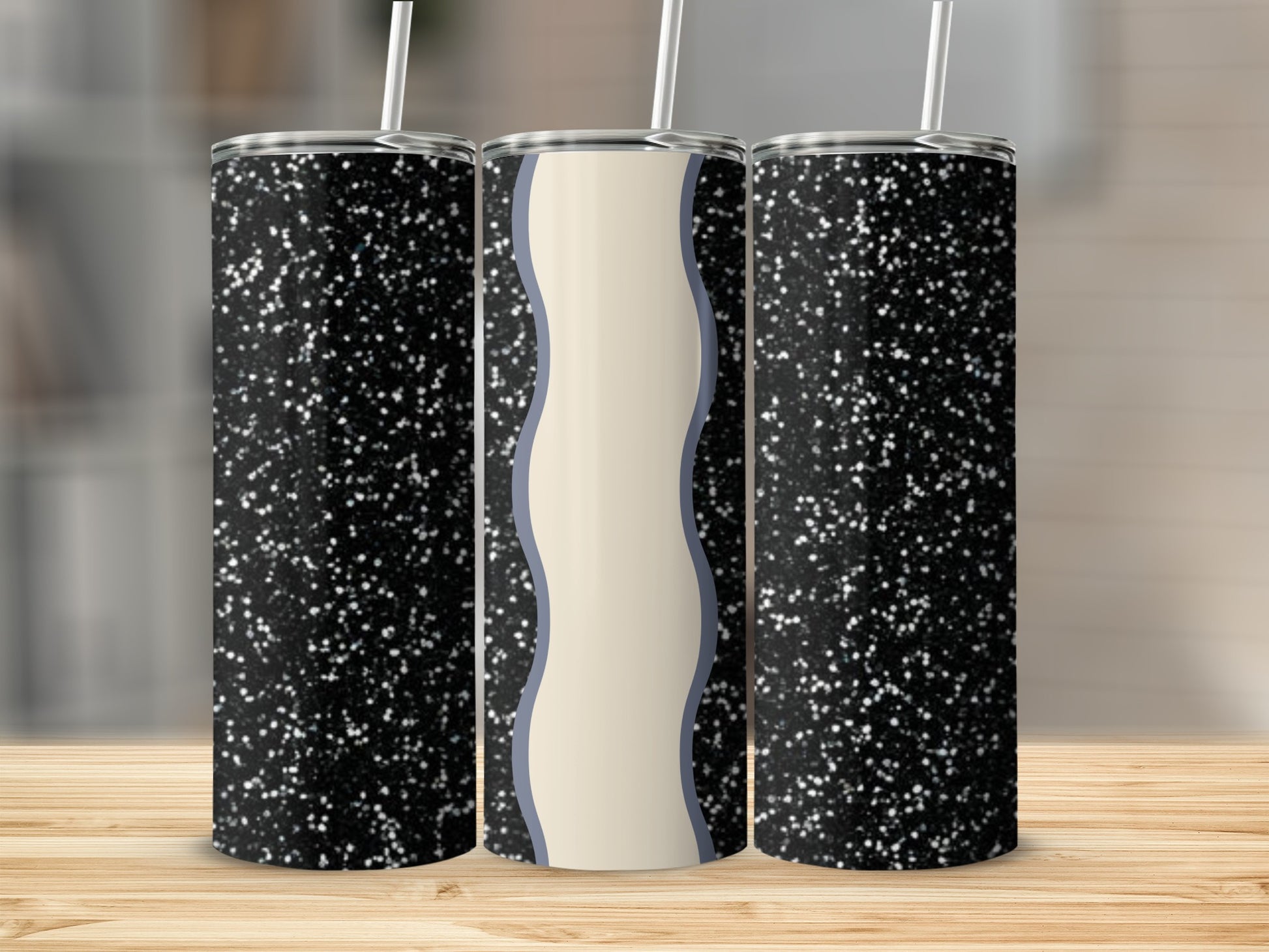 Three glitter tumblers with wavy cream and blue design on a wooden surface.