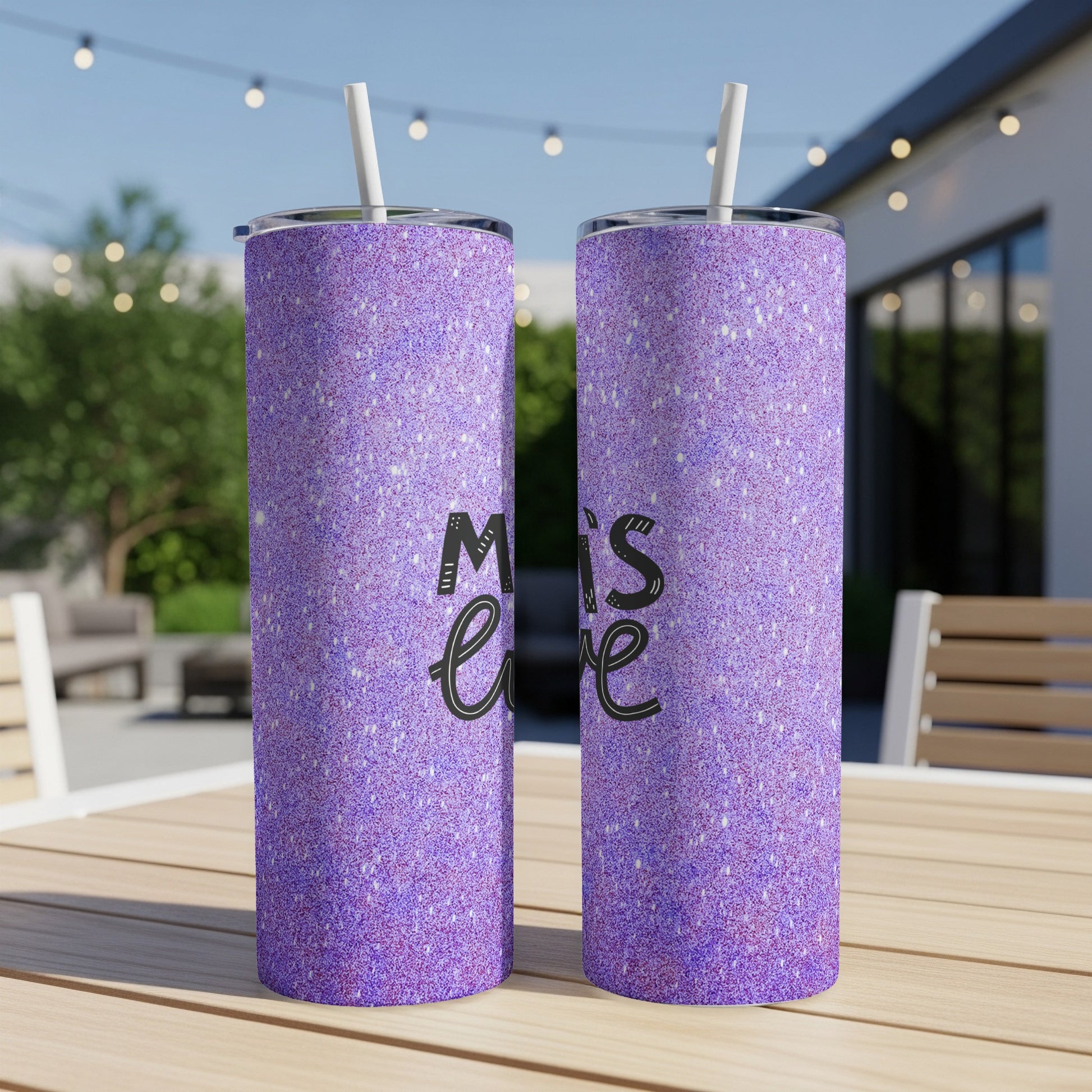 Two purple glitter tumblers with "Mom's" text on a wooden table outdoors.