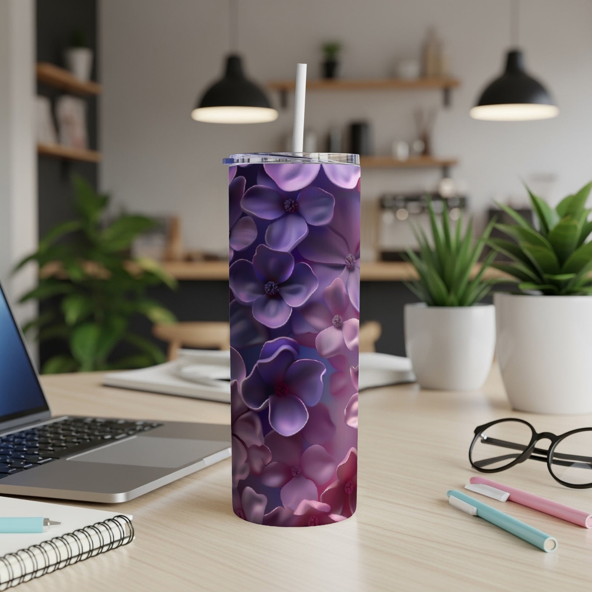Purple floral tumbler on desk with laptop and pens.