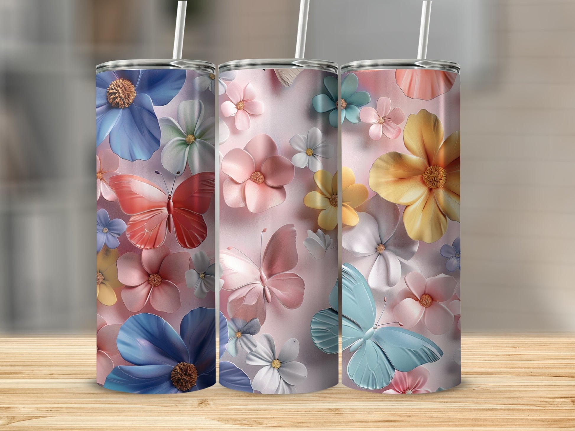 Three tumblers with butterfly and floral designs on a wooden surface.