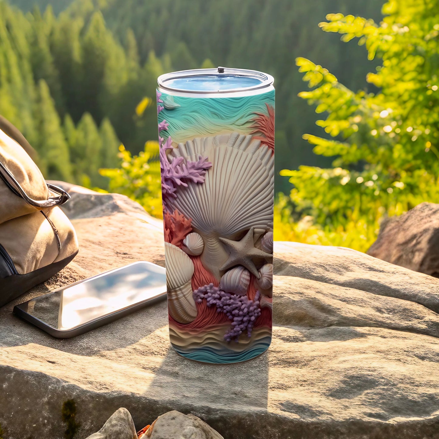 Seashell and coral decorated tumbler on rocky surface with backpack and phone.