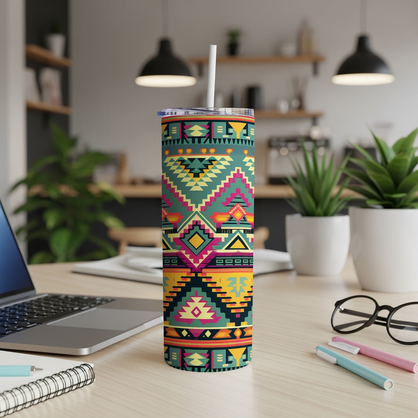 Tribal pattern skinny tumbler with straw on a desk with a laptop and pens.