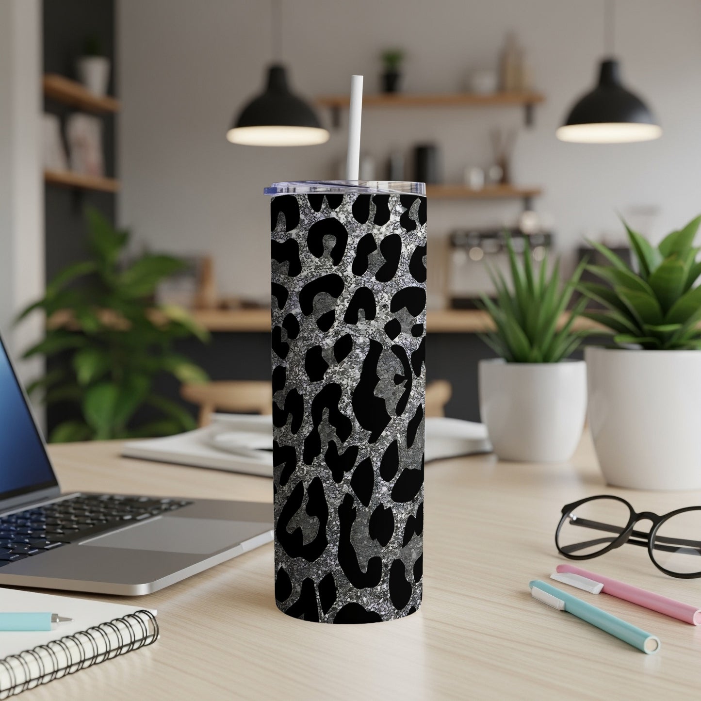 Leopard print skinny tumbler with straw on a desk.