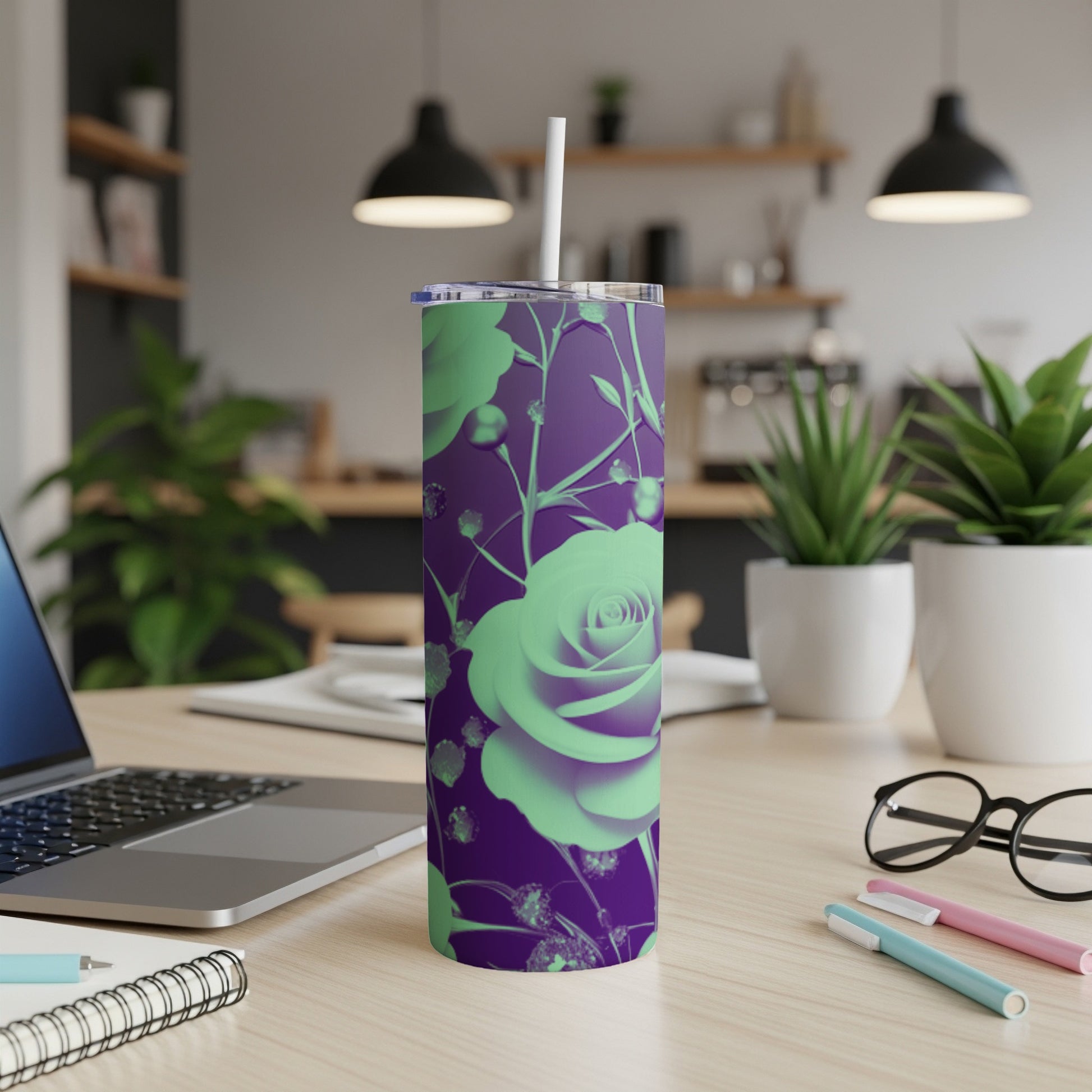 Purple tumbler with green rose pattern, straw inserted, on a desk.
