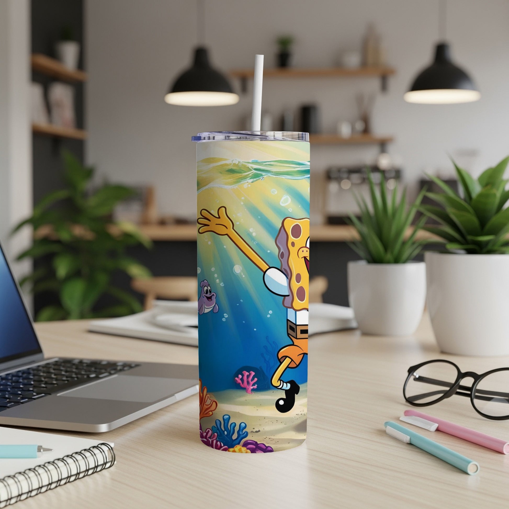 SpongeBob SquarePants on a blue, underwater-themed tumbler with straw, on a desk.
