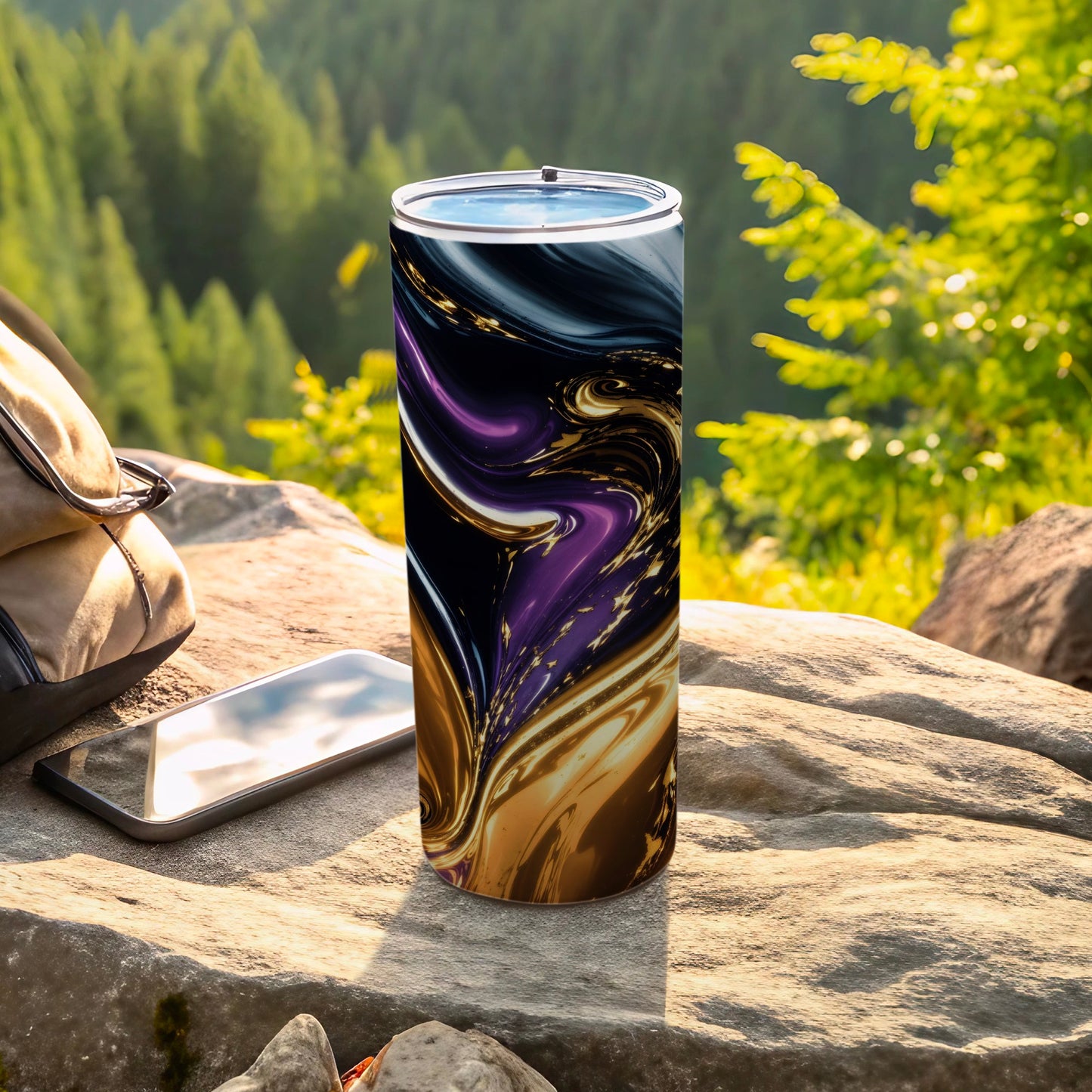 Tumbler with swirling purple, gold, and black abstract design on outdoor rock.