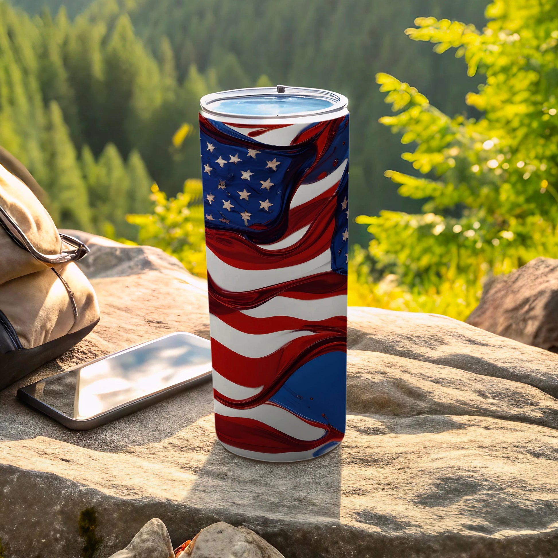American flag tumbler on rock with phone and backpack.