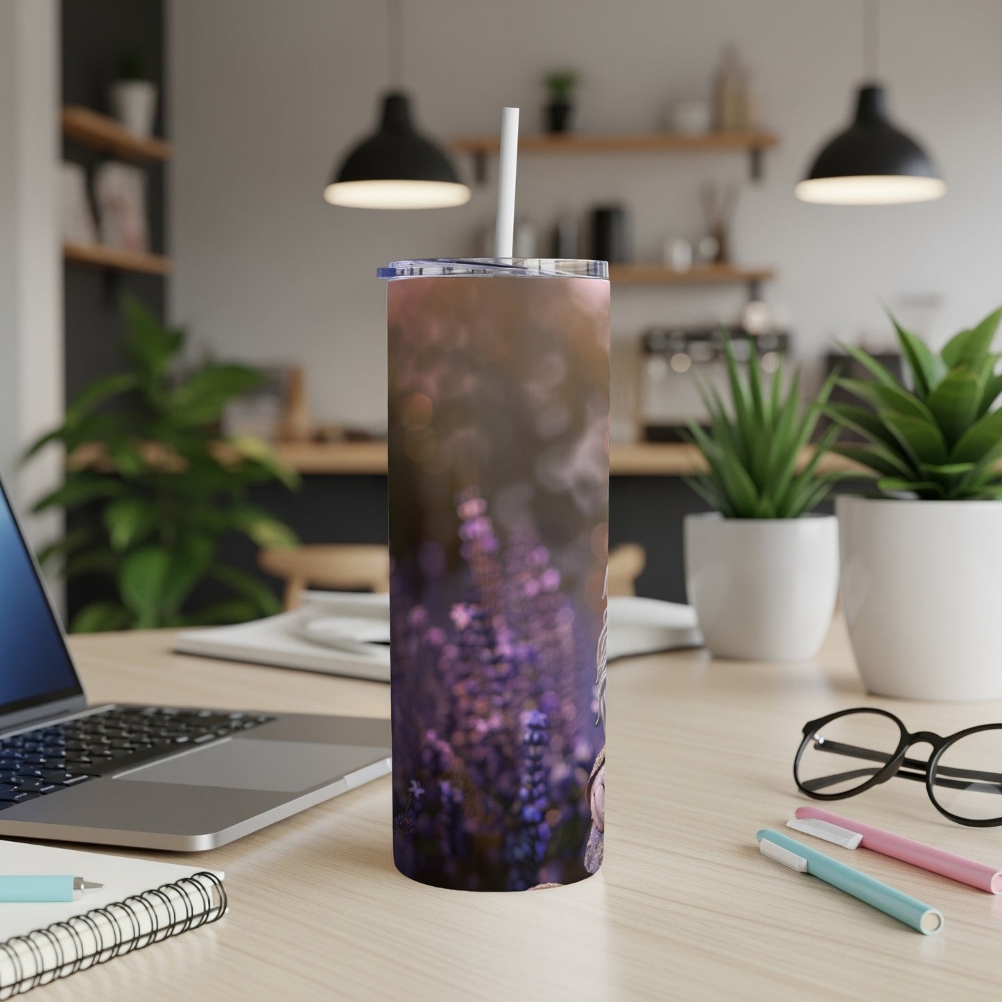 Purple floral tumbler with straw on a desk next to a laptop.