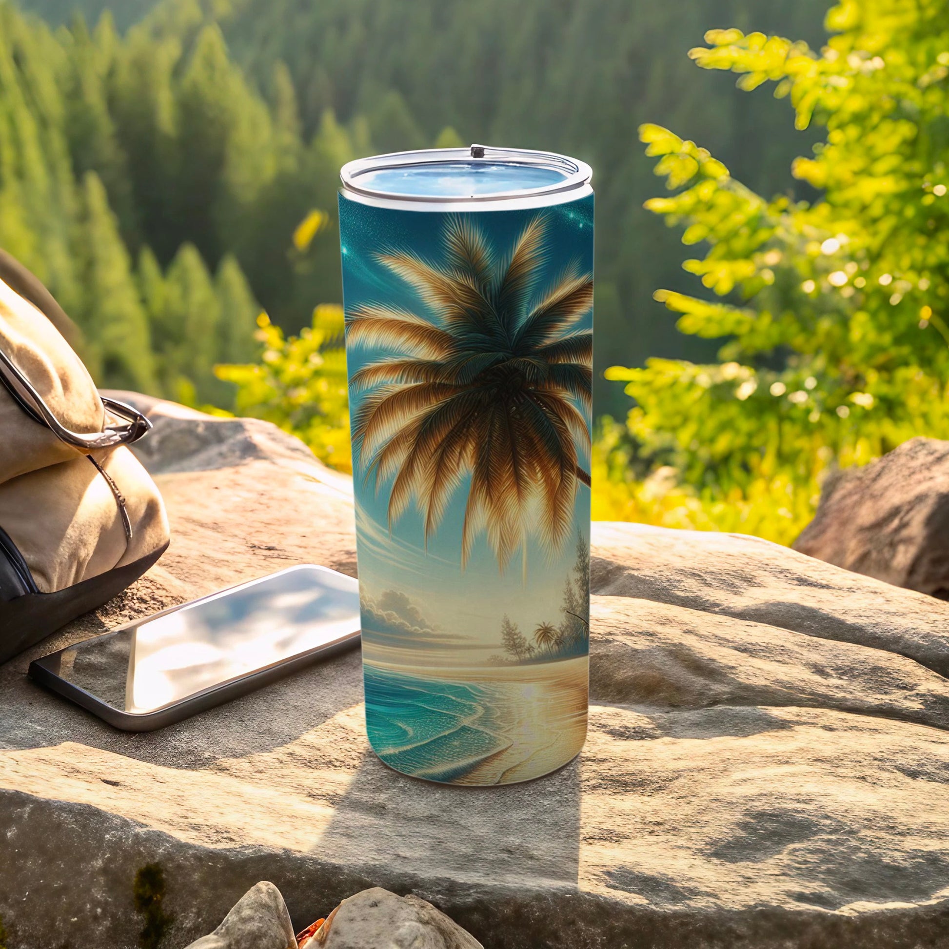 Tall tumbler with palm tree sunset beach scene, resting on rock near phone.
