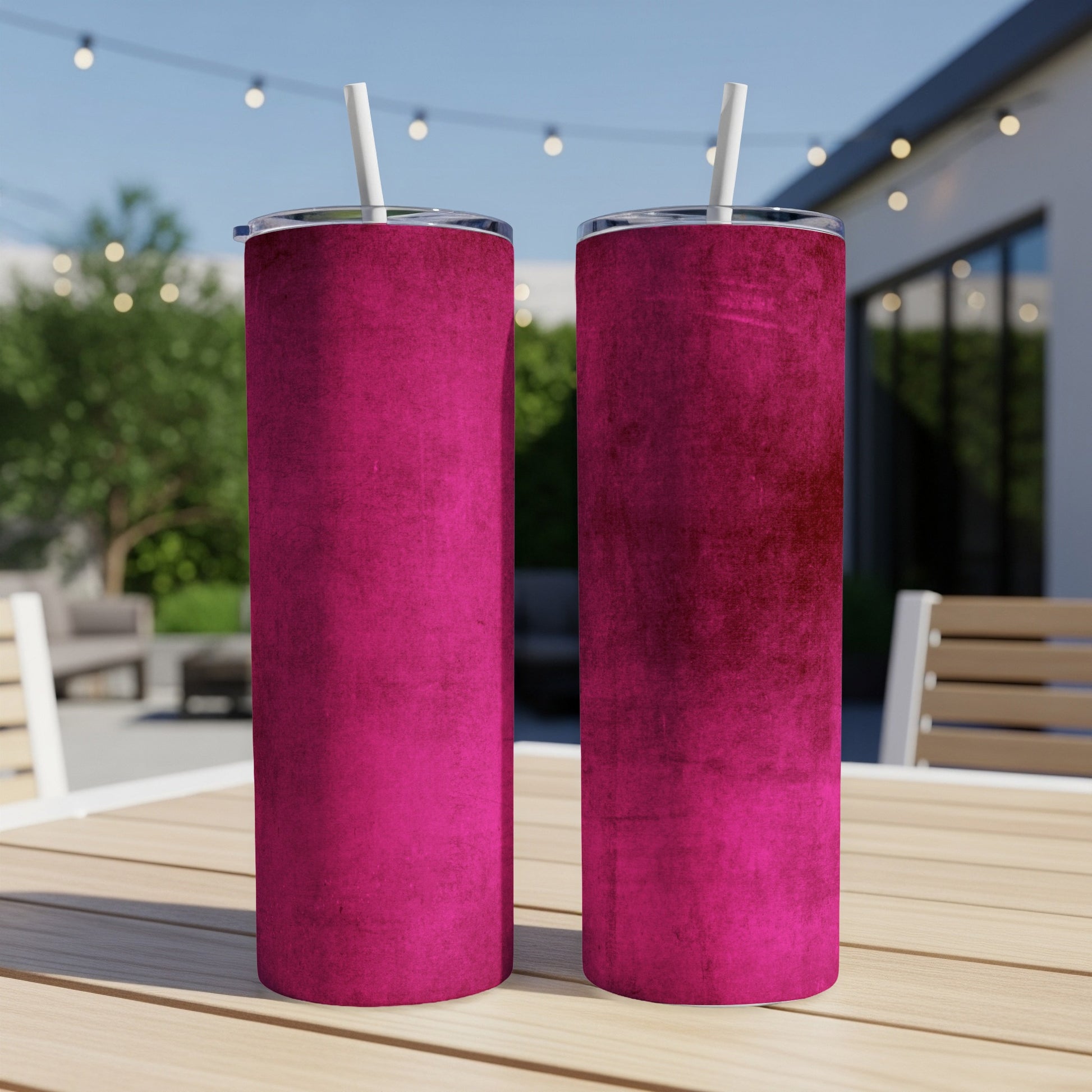 Two fuchsia textured tumblers with white straws on a wooden table.