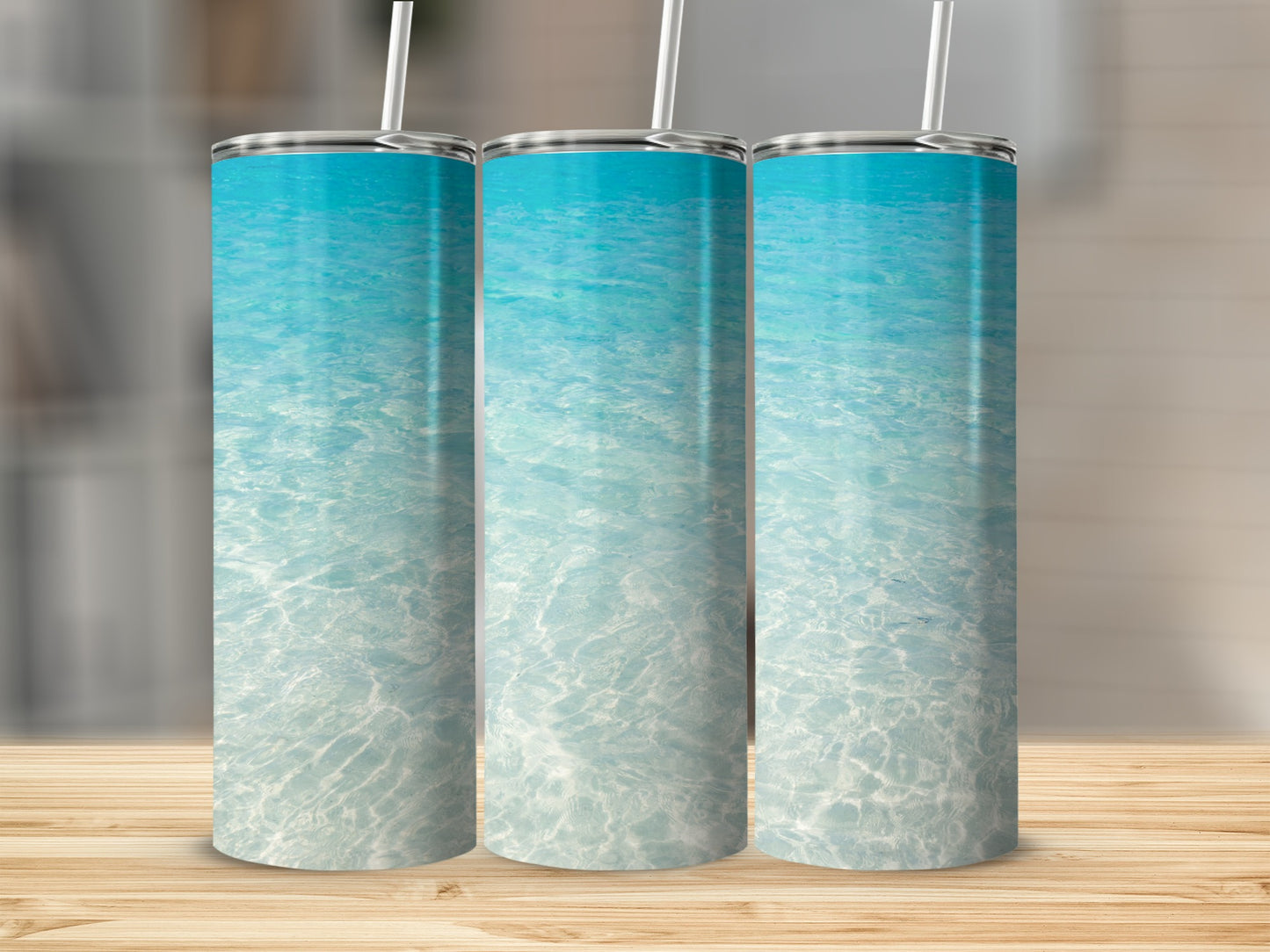 Three tumblers with a blue ocean water and sand design.