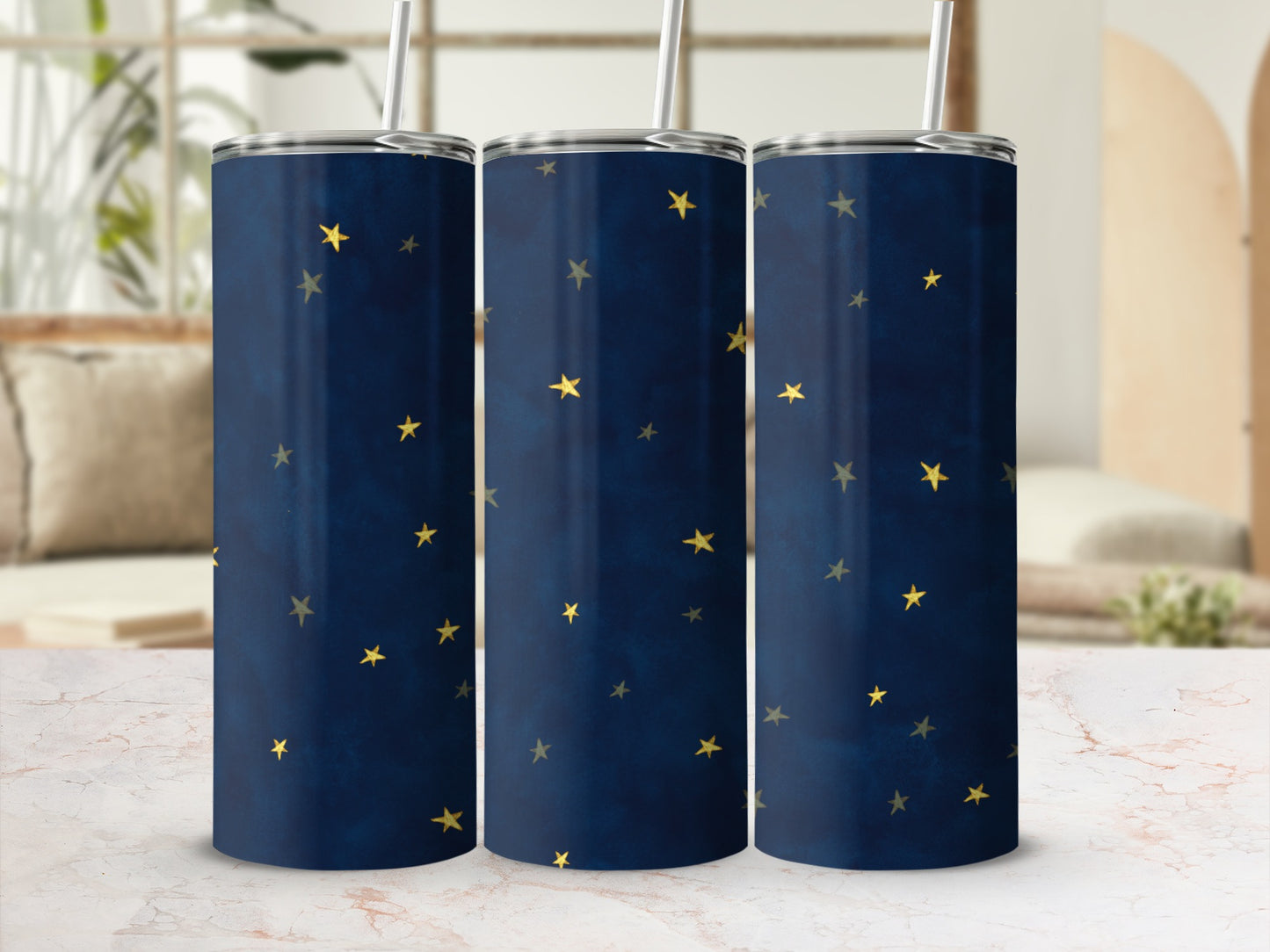Three dark blue tumblers with a scattered gold star pattern and metal straws.