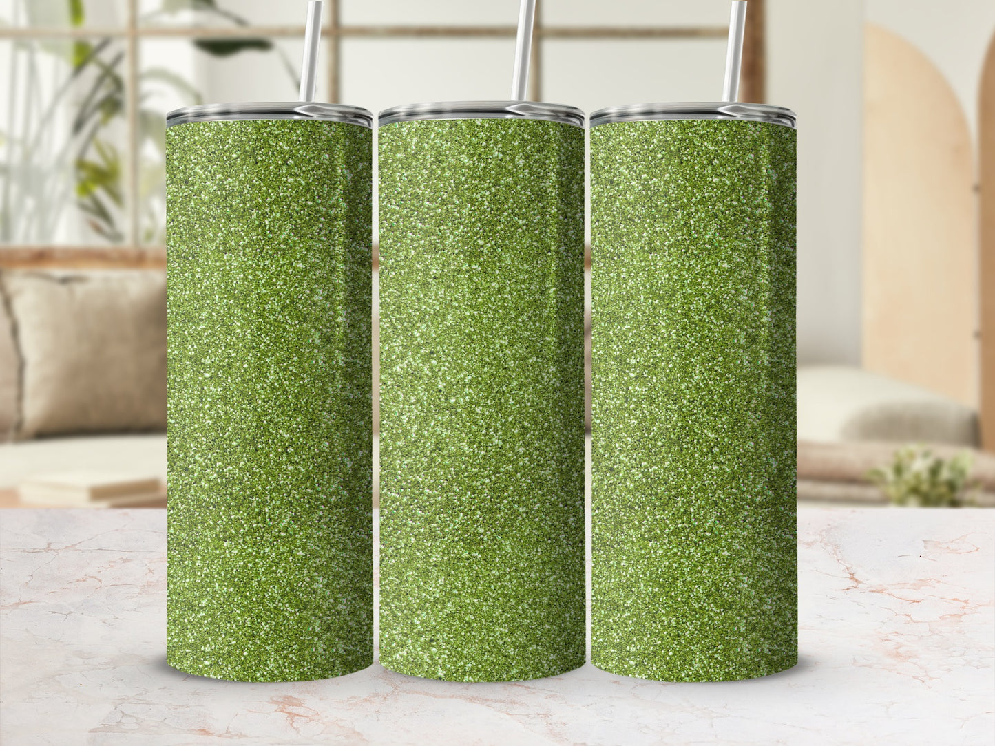Three green glitter tumblers with straws lined up on a marble surface.