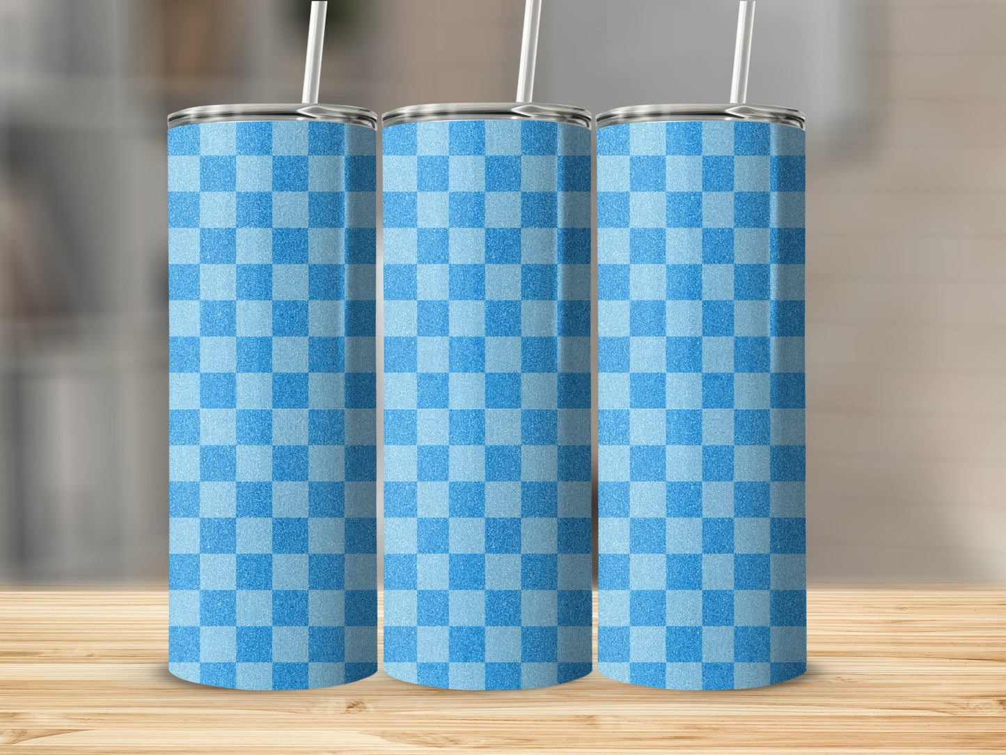 Three blue and light blue checkered tumblers with straws on a wooden surface.