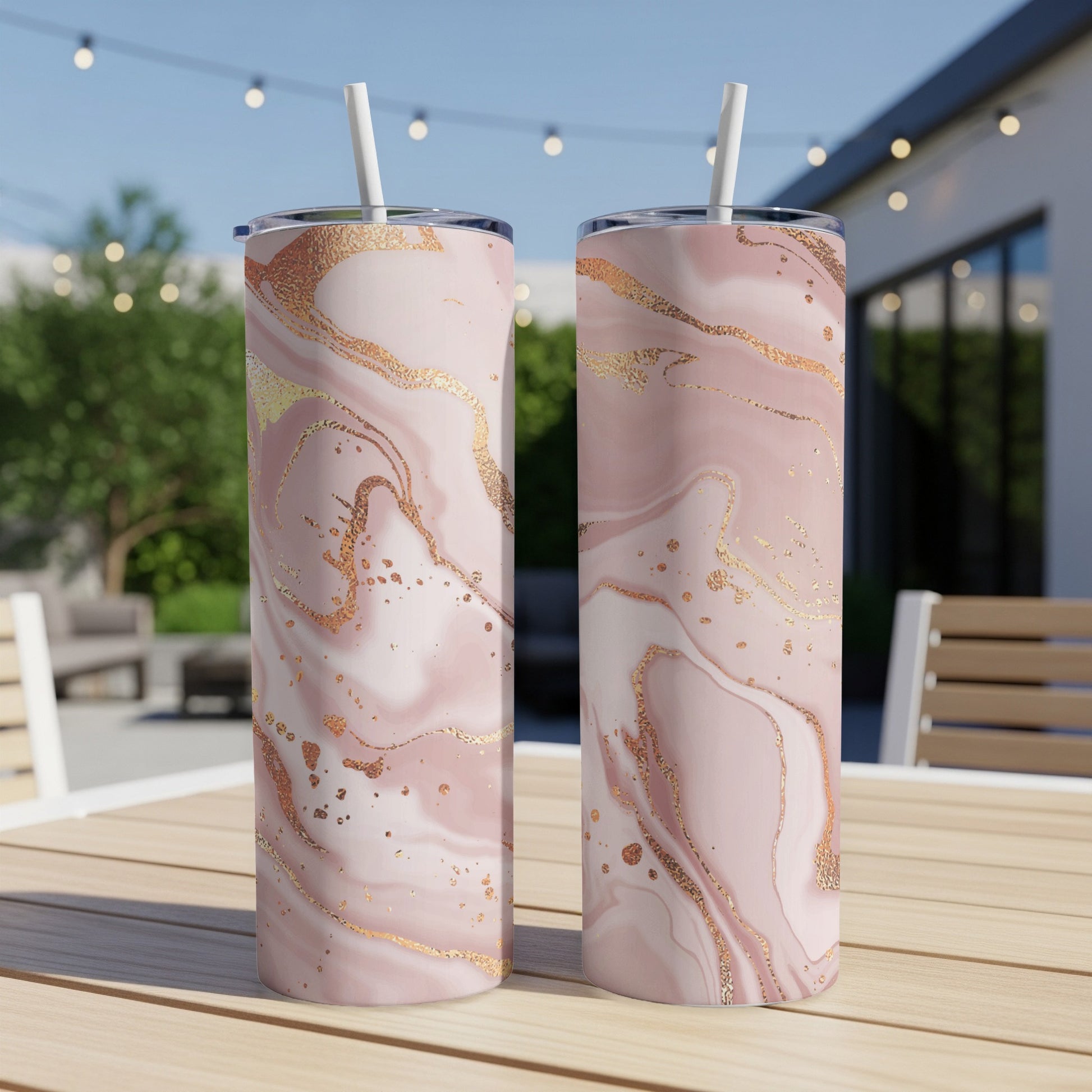 Two pink marbled tumblers with gold accents on a wooden table.