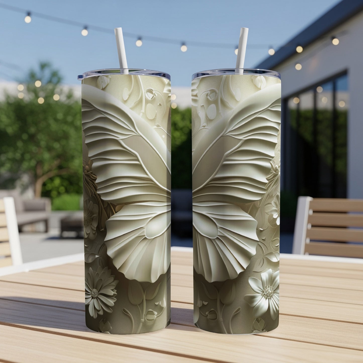 Two tall, tapered tumblers with embossed butterfly and floral designs on a table.