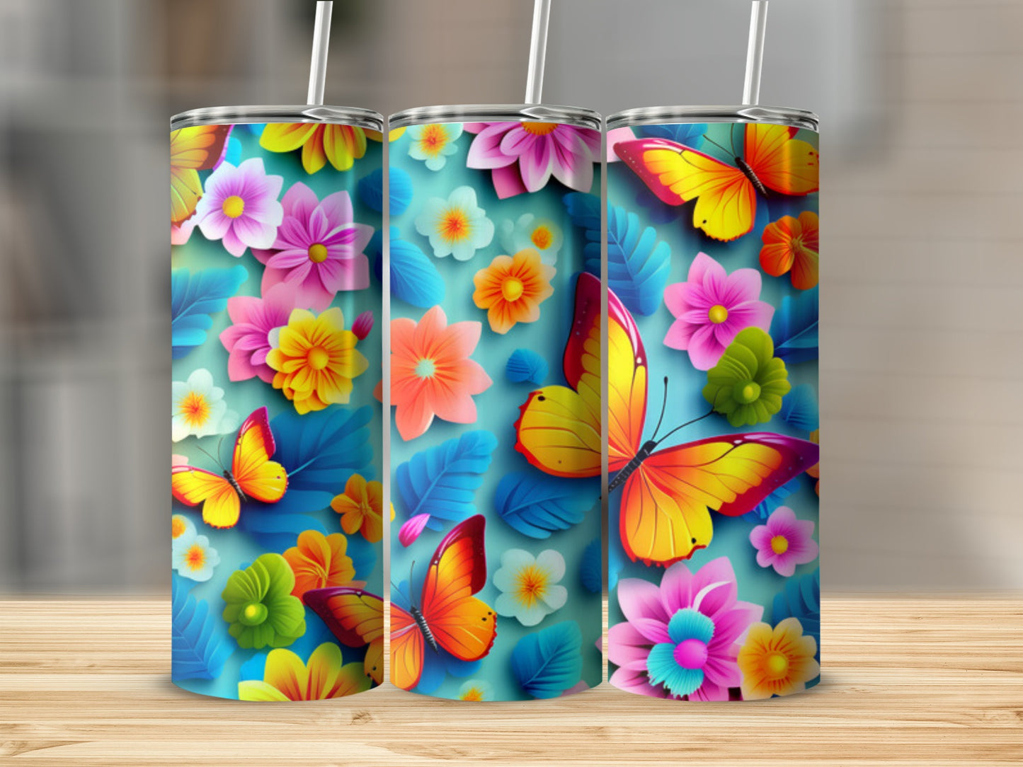 Three tumblers with colorful butterflies and floral designs on a wooden surface.