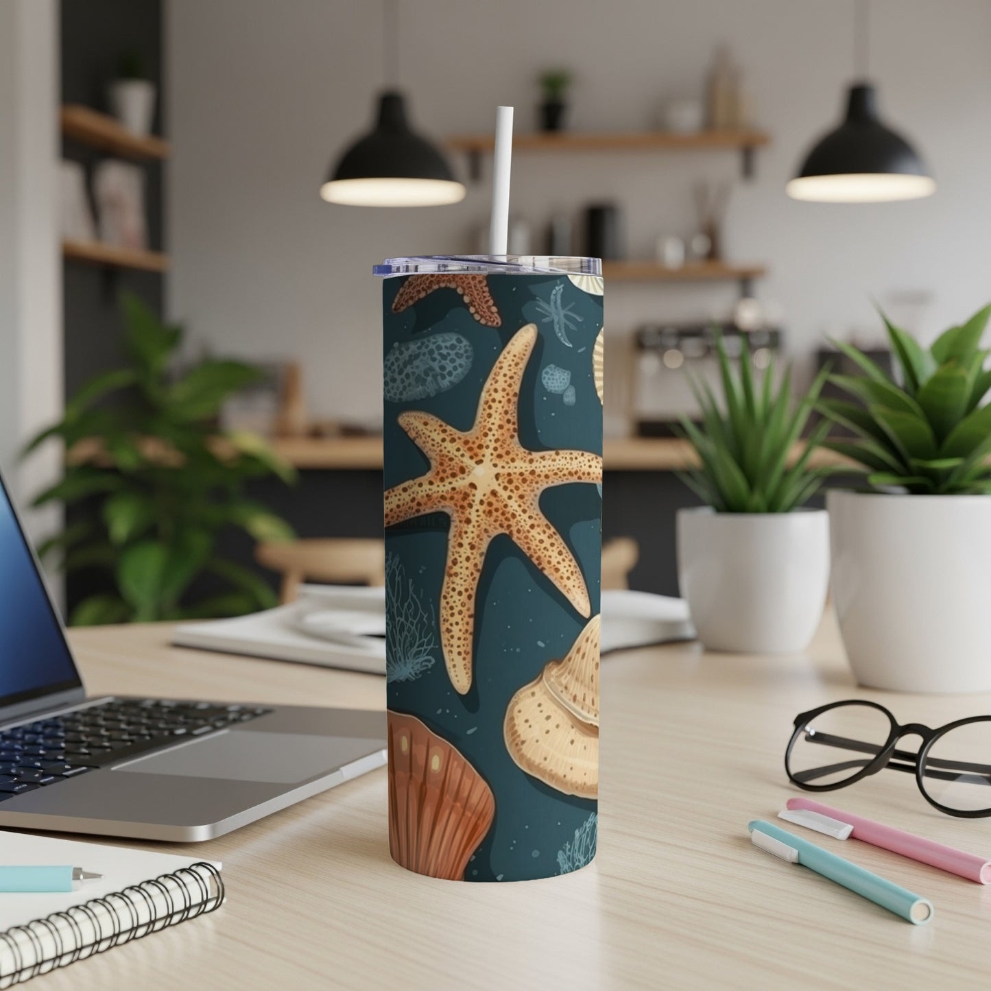 Tall tumbler with starfish and seashell pattern, straw inserted.