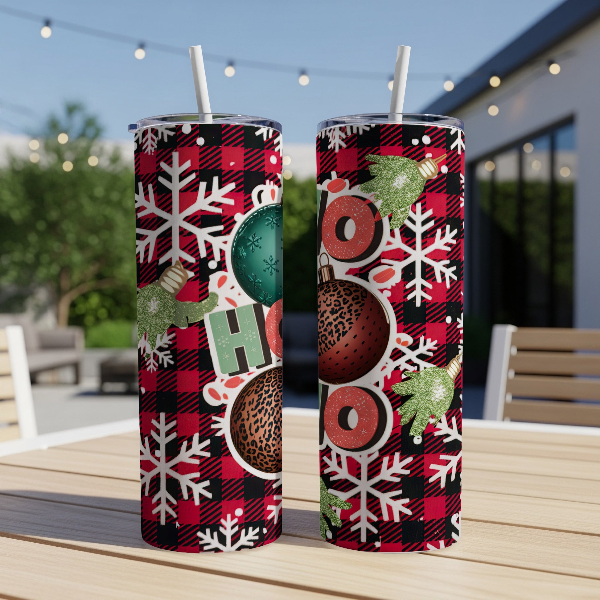 Two tumblers with "HO HO HO" and Christmas patterns on a table.