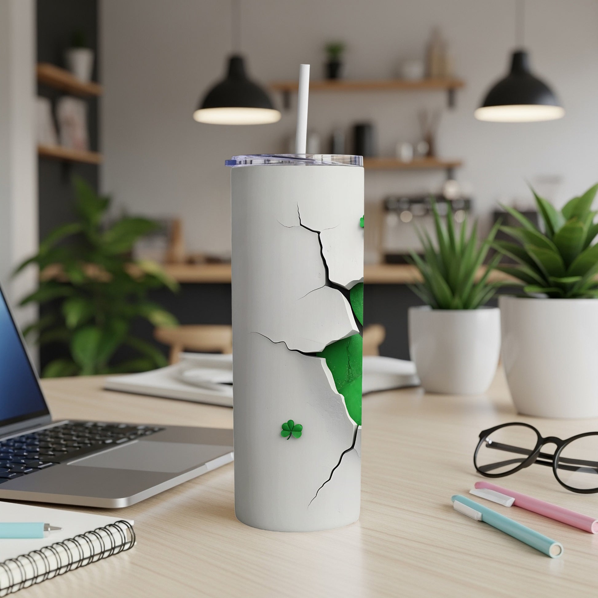 White tumbler with cracked design revealing green shamrocks and a straw.