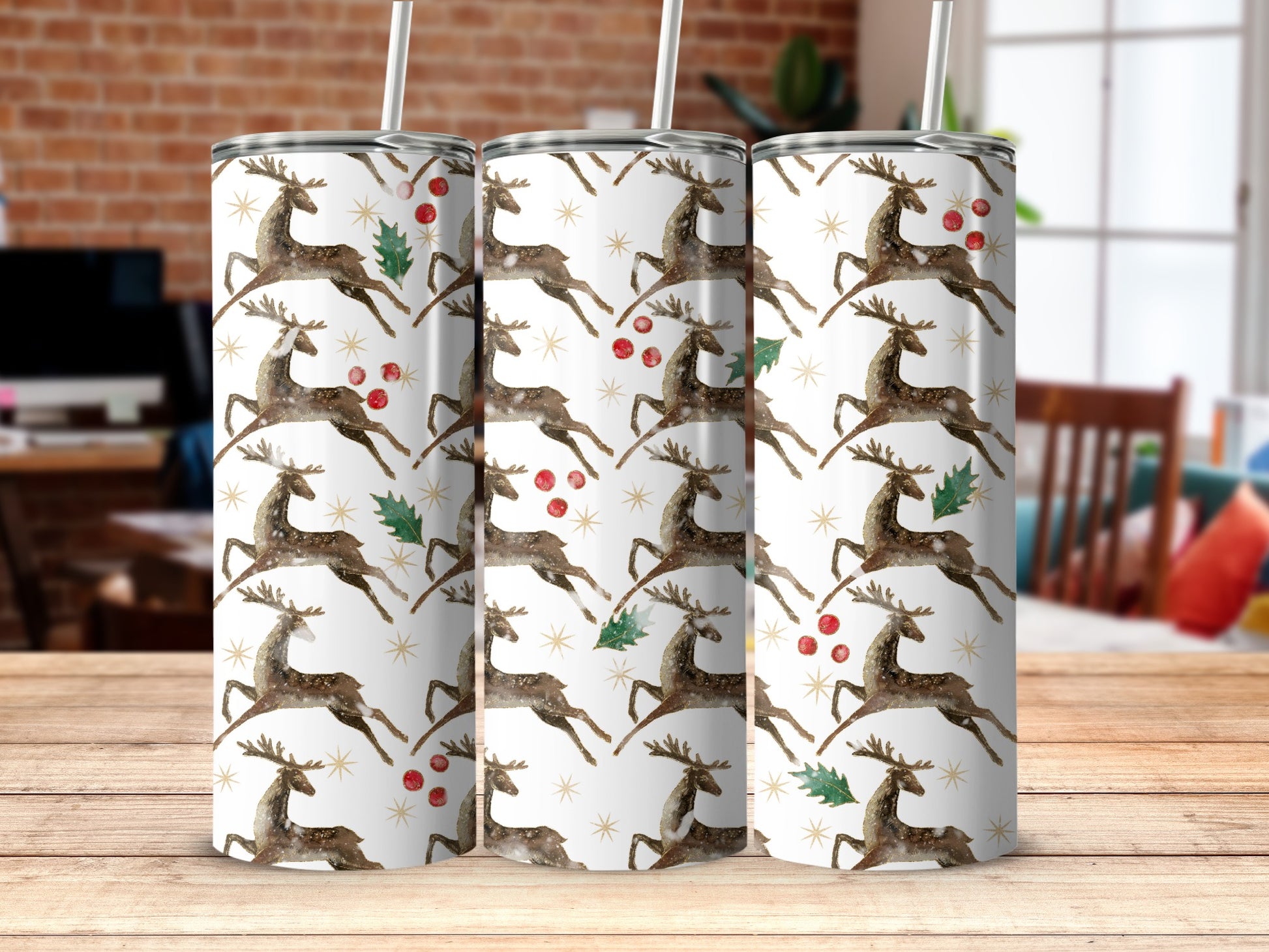 Three tumblers with a pattern of leaping reindeer, holly, and snowflakes.