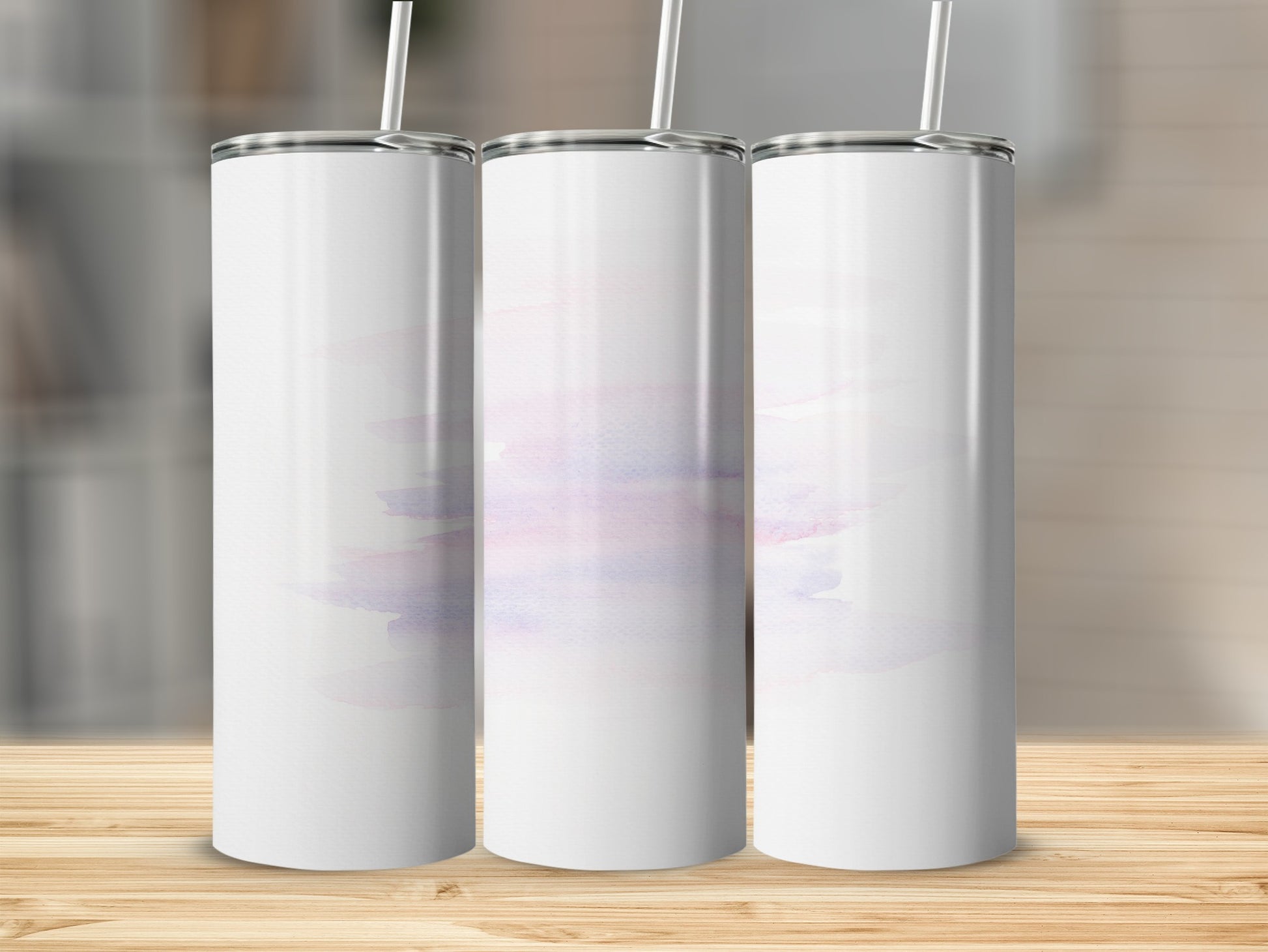 Three blank white tumblers with pastel watercolor wash on a wooden surface.