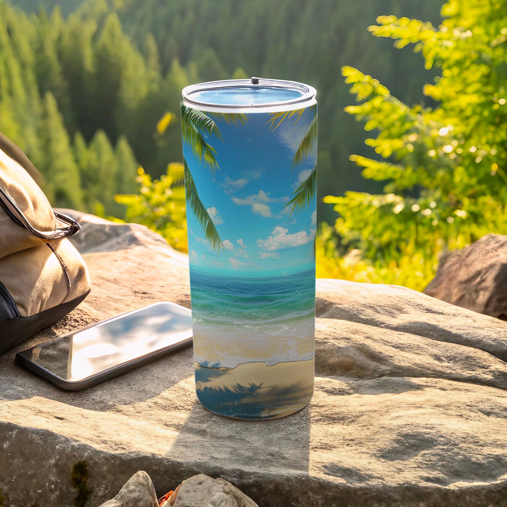 Tumbler with tropical beach scene and palm trees, resting on rocks.