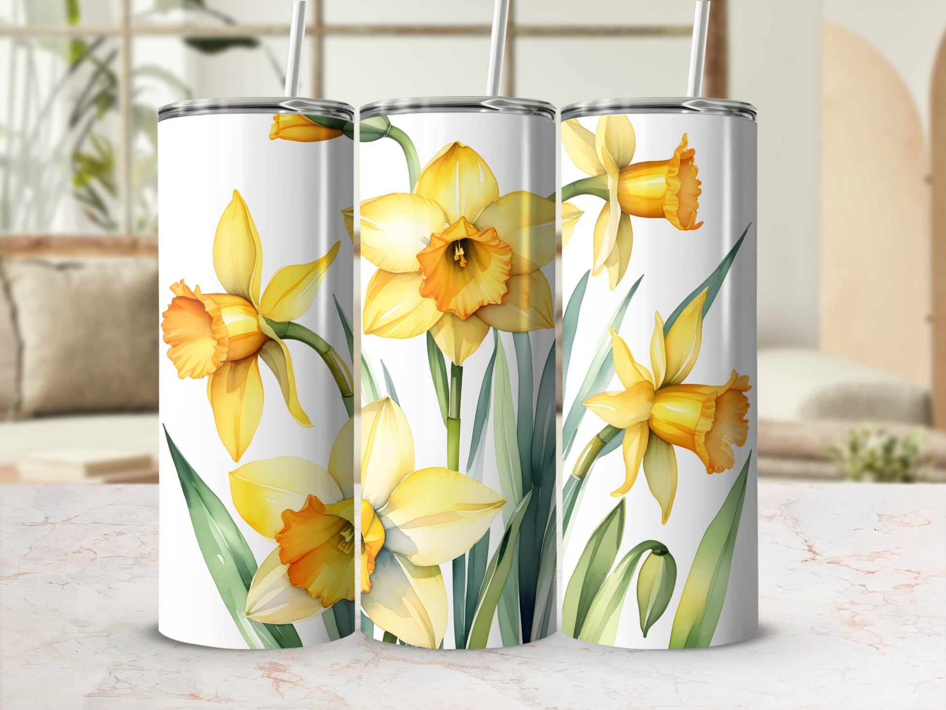 Three tumblers with a watercolor daffodil floral design on a marble surface.