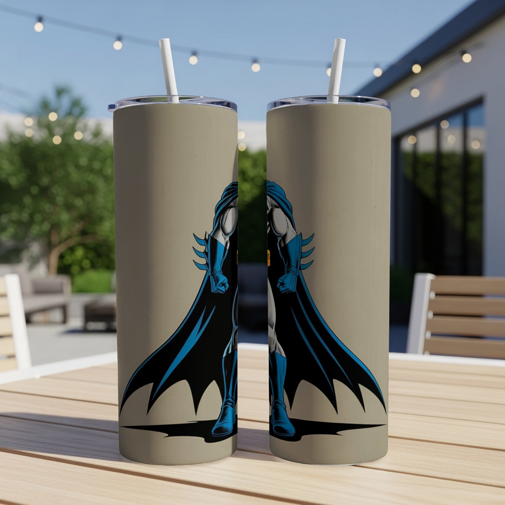 Two tan tumblers with Batman graphic, standing on a table outdoors.