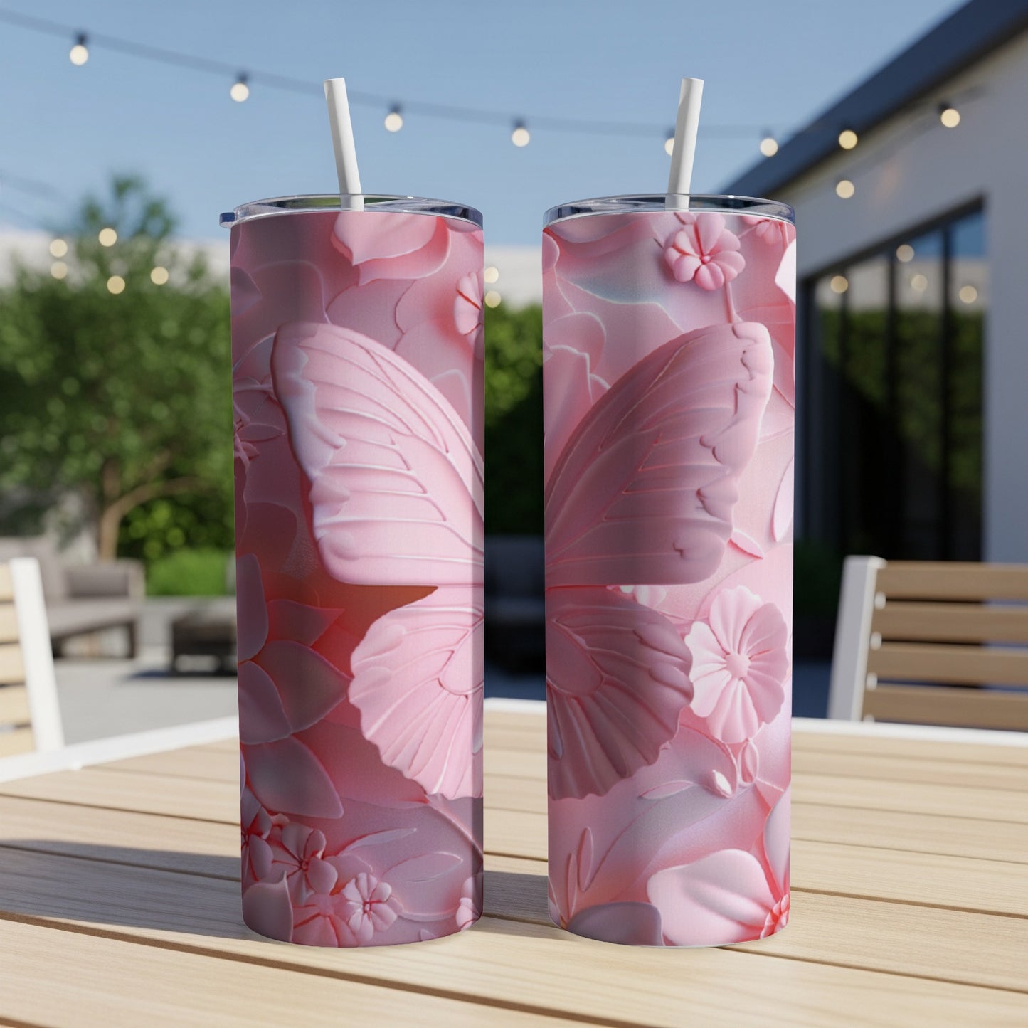 Two pink tumblers with floral and butterfly embossed designs on a wooden table.