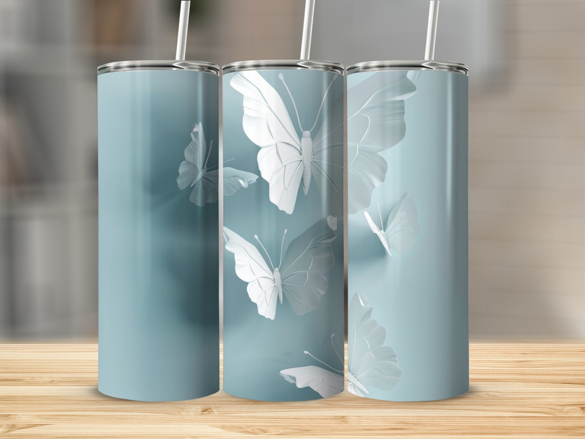 Three blue tumblers with raised white butterfly designs and straws.