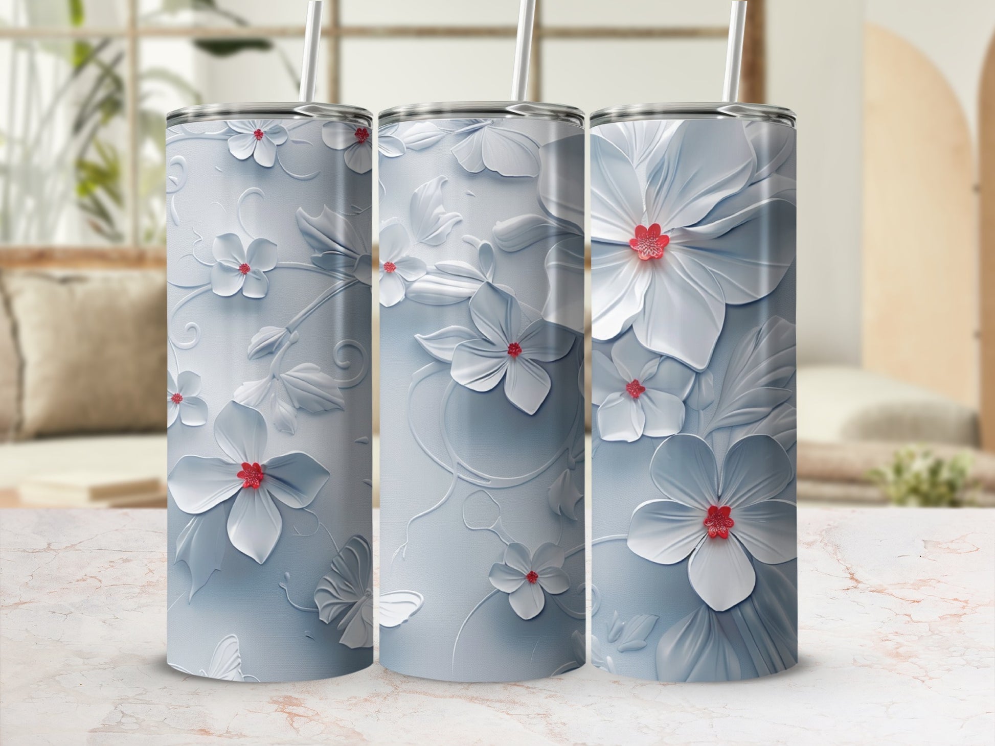 Three white floral tumblers with red flower centers on a marbled countertop.