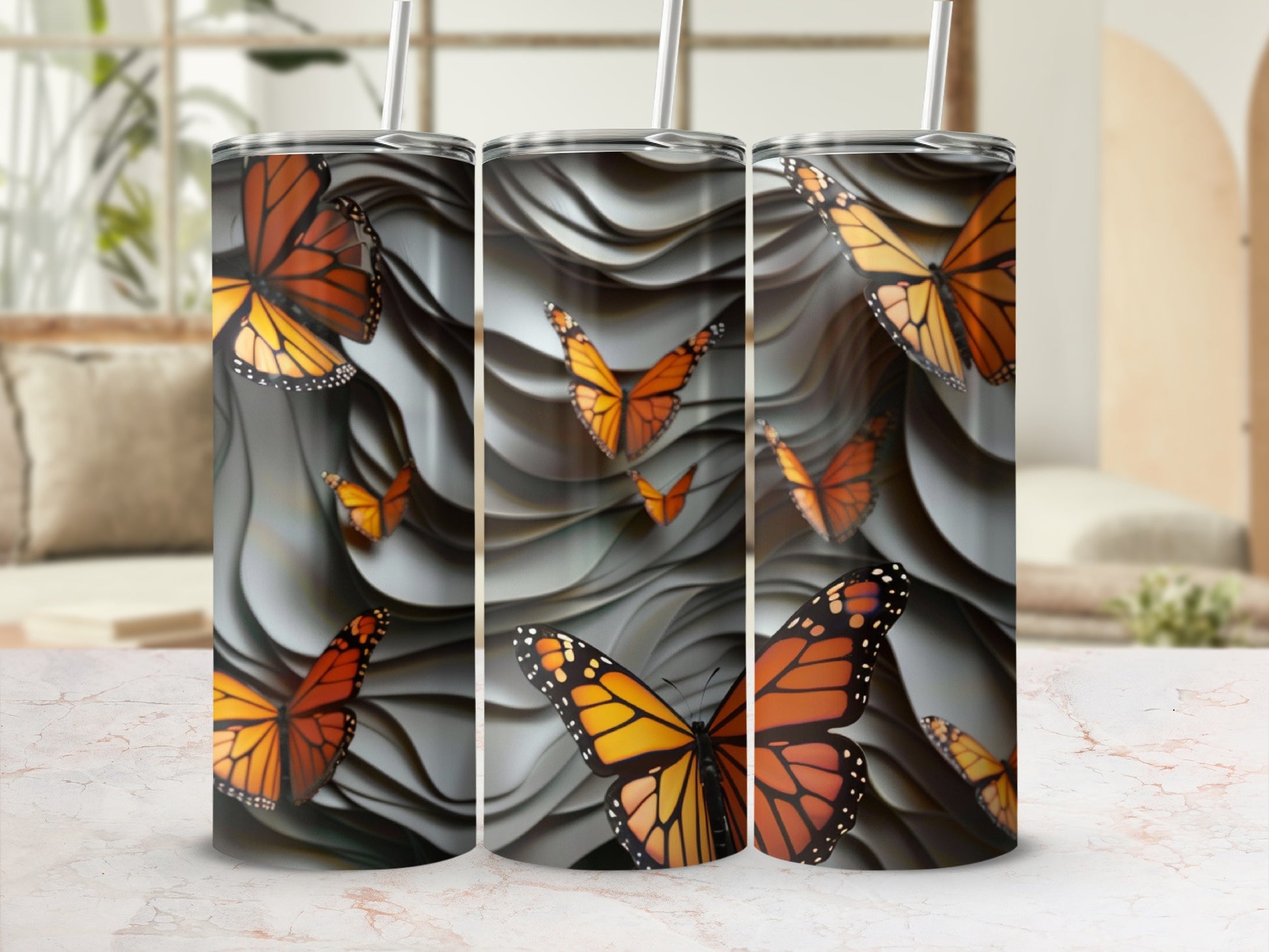 Three tumblers with orange and black monarch butterflies on a wavy grey background.