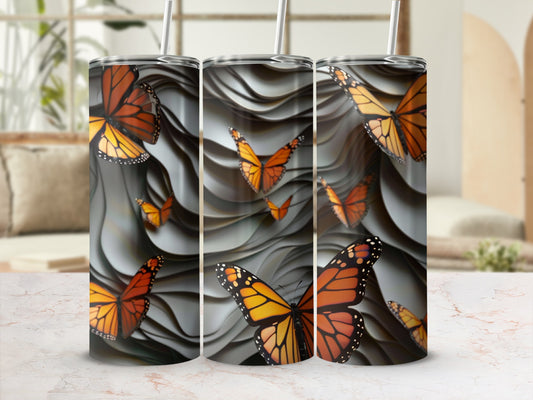 Three tumblers with orange and black monarch butterflies on a wavy grey background.