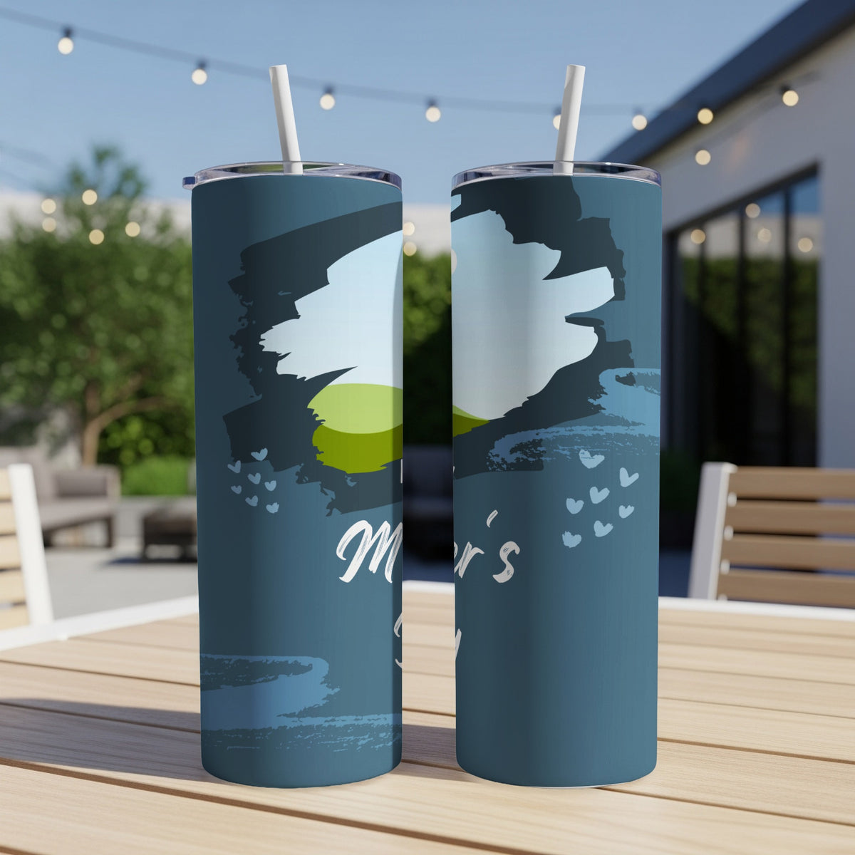 Two tumblers with a blue design and "Mother's Day" text sit on a wooden table.