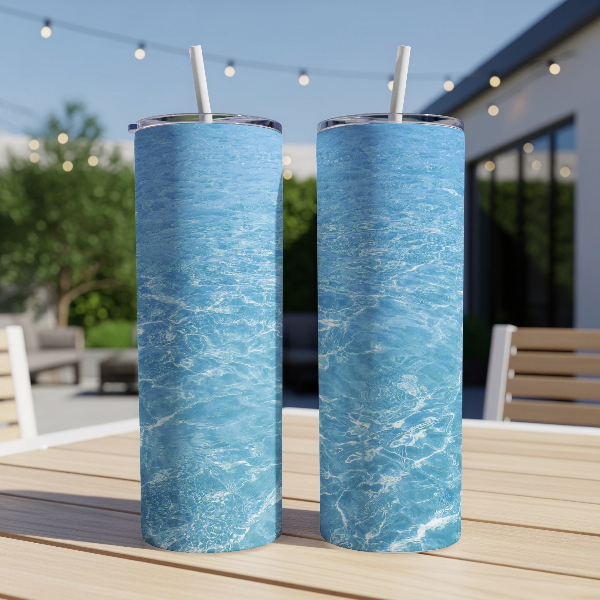Two tall tumblers with a rippling blue water design on a wooden table.