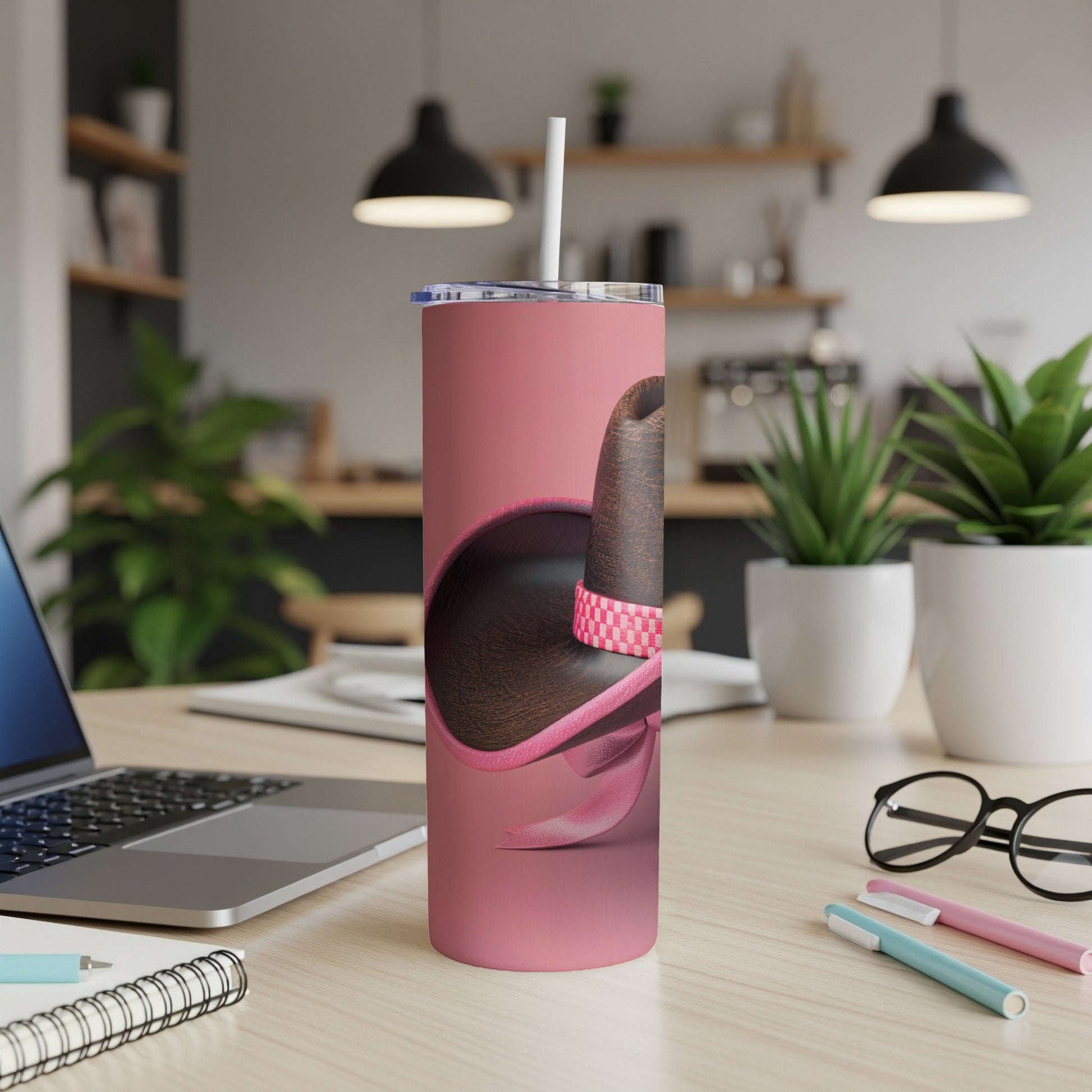 Pink tumbler with a sombrero design and white straw on a desk.